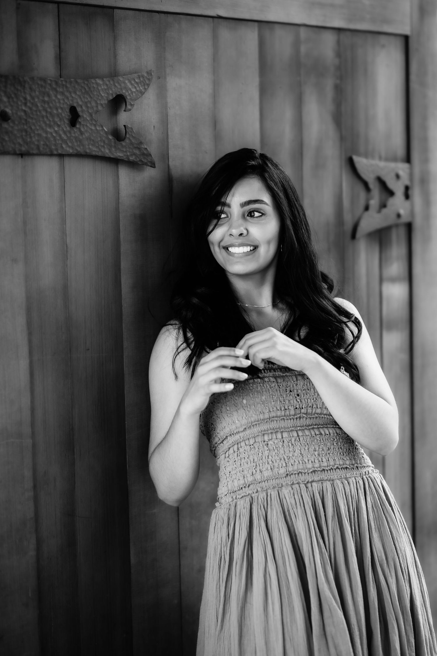 A black and white portrait against wooden panels showing someone in a gathered dress.