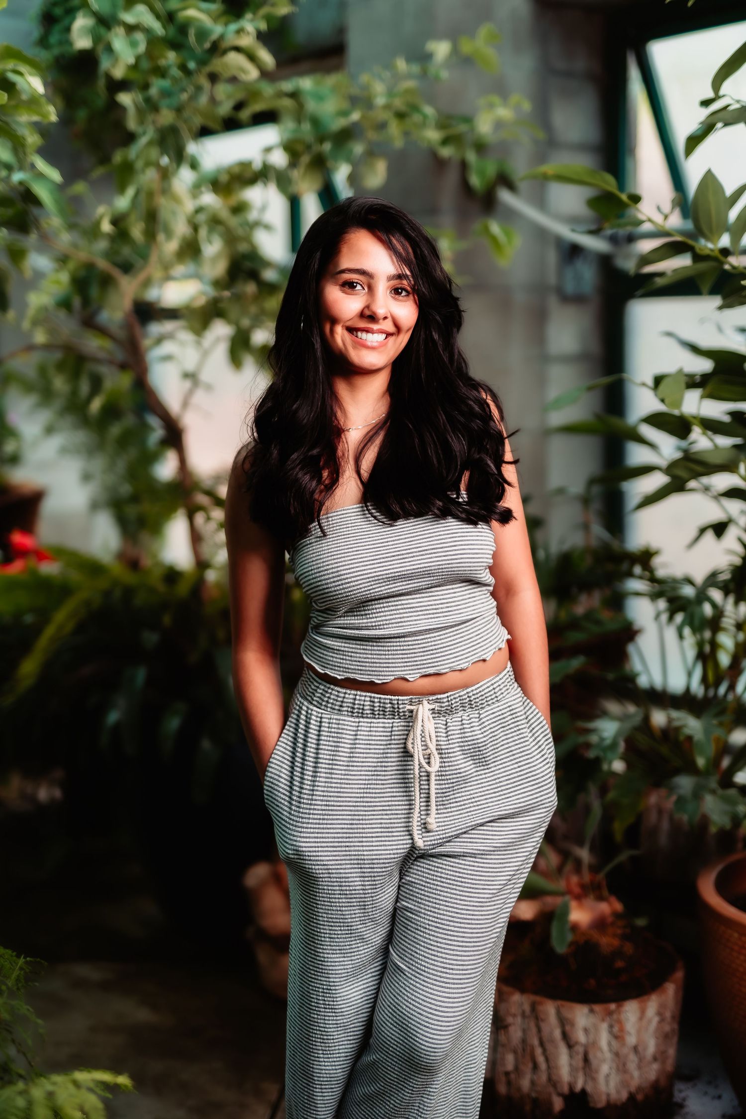 Portrait in a garden setting wearing casual gray loungewear among potted plants.