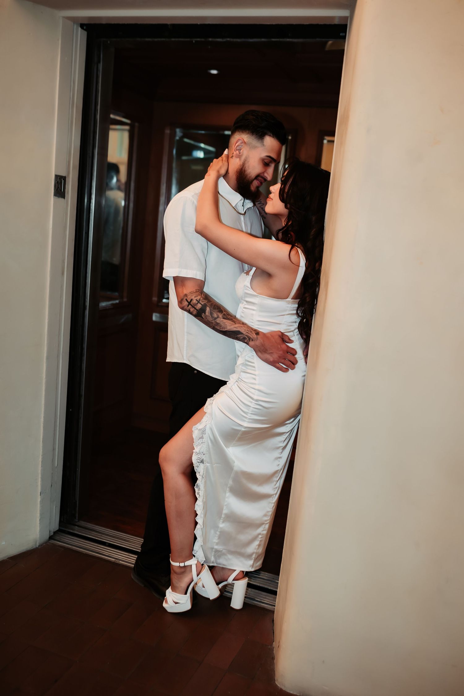 Romantic couple embracing in a doorway wearing coordinating white outfits.