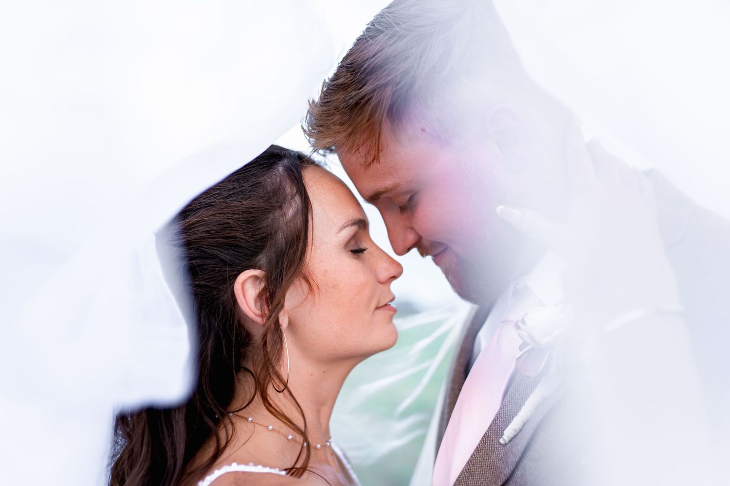 Intimate romantic moment between newlyweds captured in dreamy ethereal lighting.
