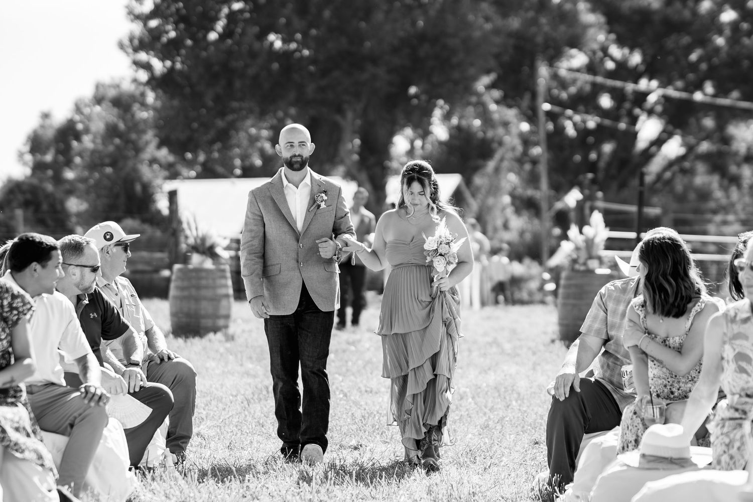 A black and white candid shot of wedding guests enjoying an outdoor reception.