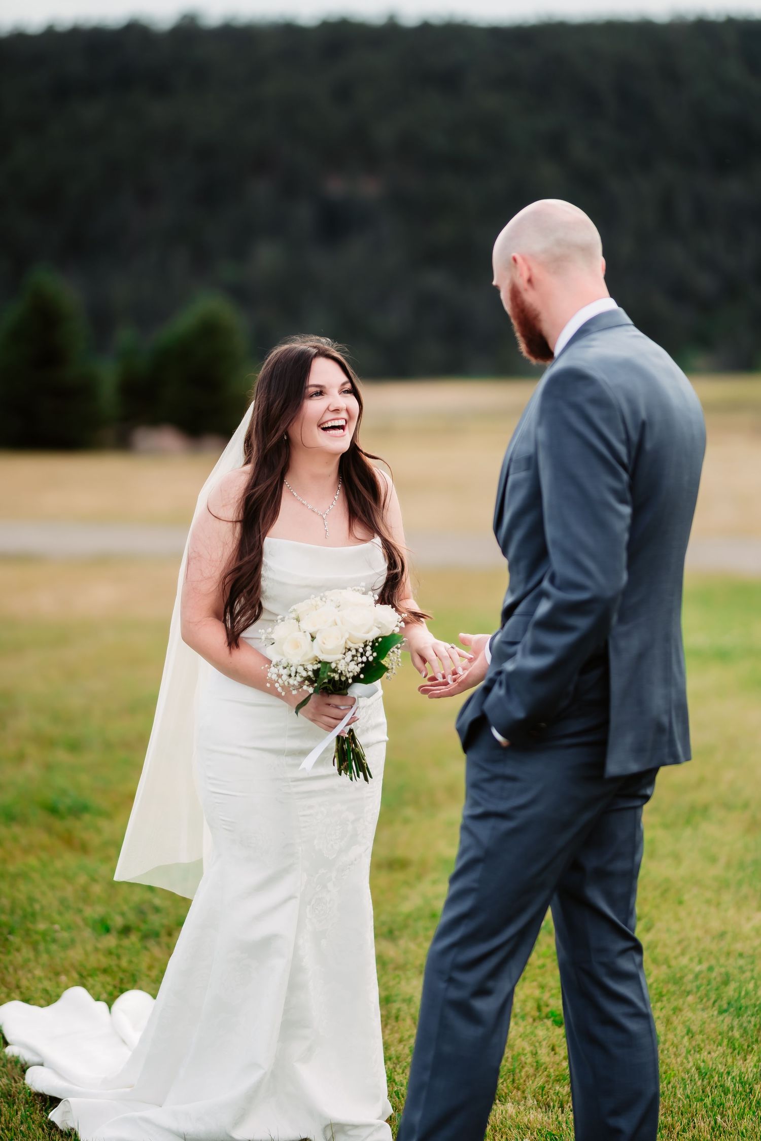 Wedding couple walks and shares a loving moment together in an outdoor field setting.