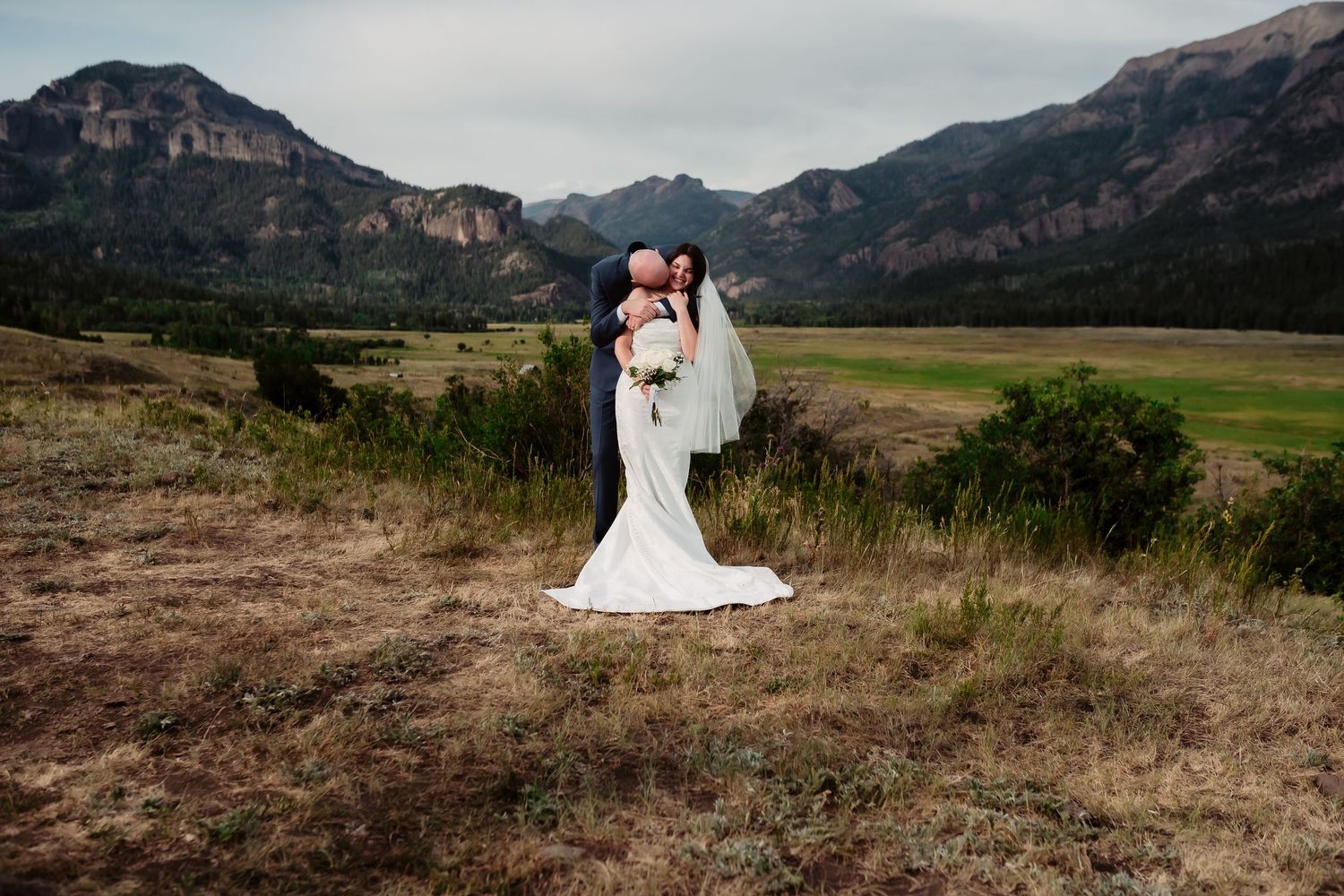 An outdoor wedding ceremony with mountains and natural scenery in the background.