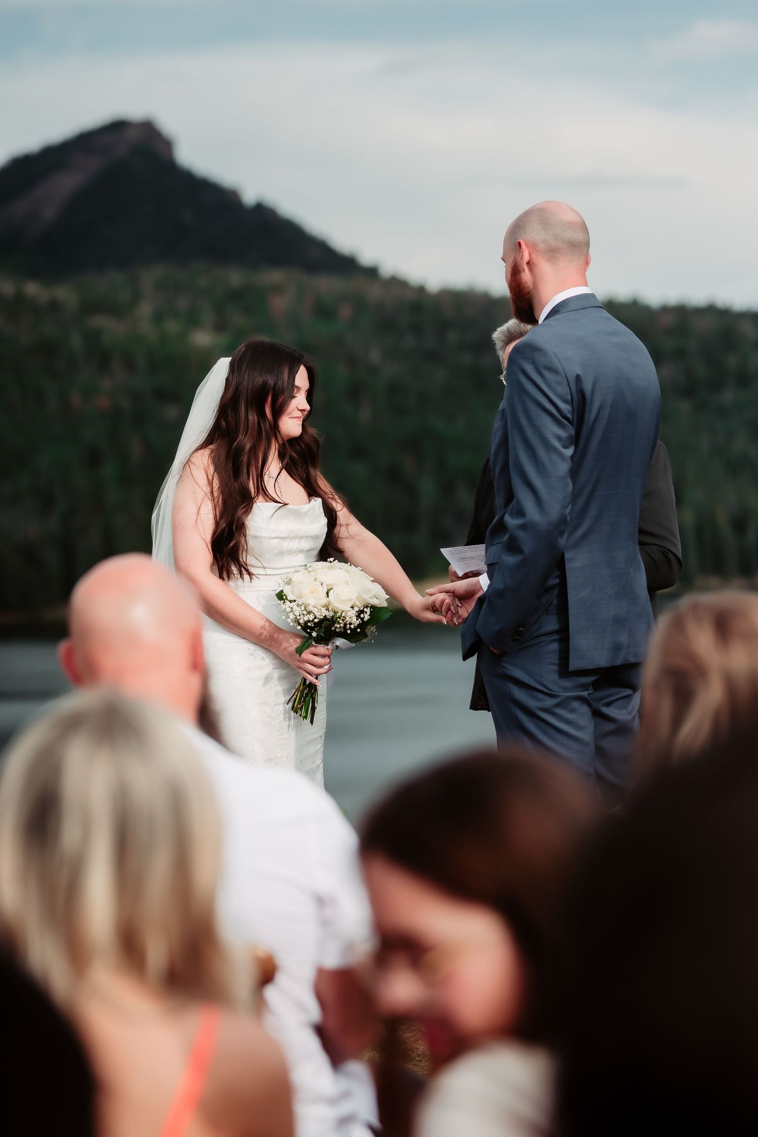 An intimate outdoor wedding ceremony unfolds beside a serene mountain lake.