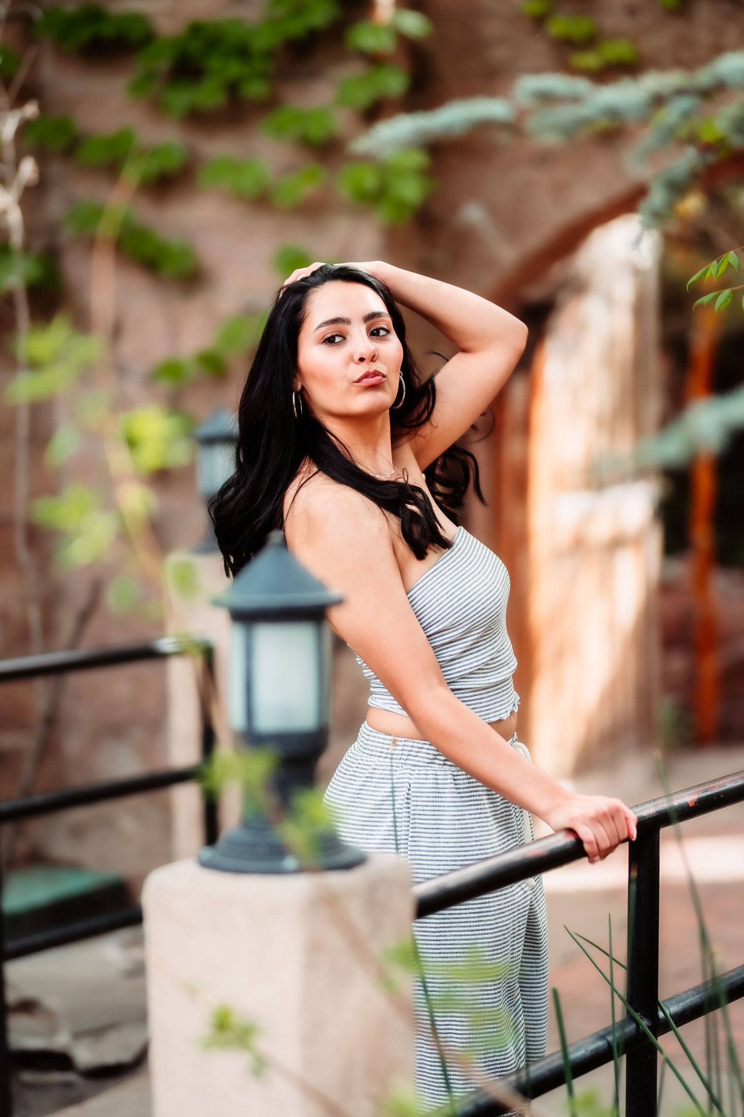 A portrait near a garden wall with a person in grey casual wear.