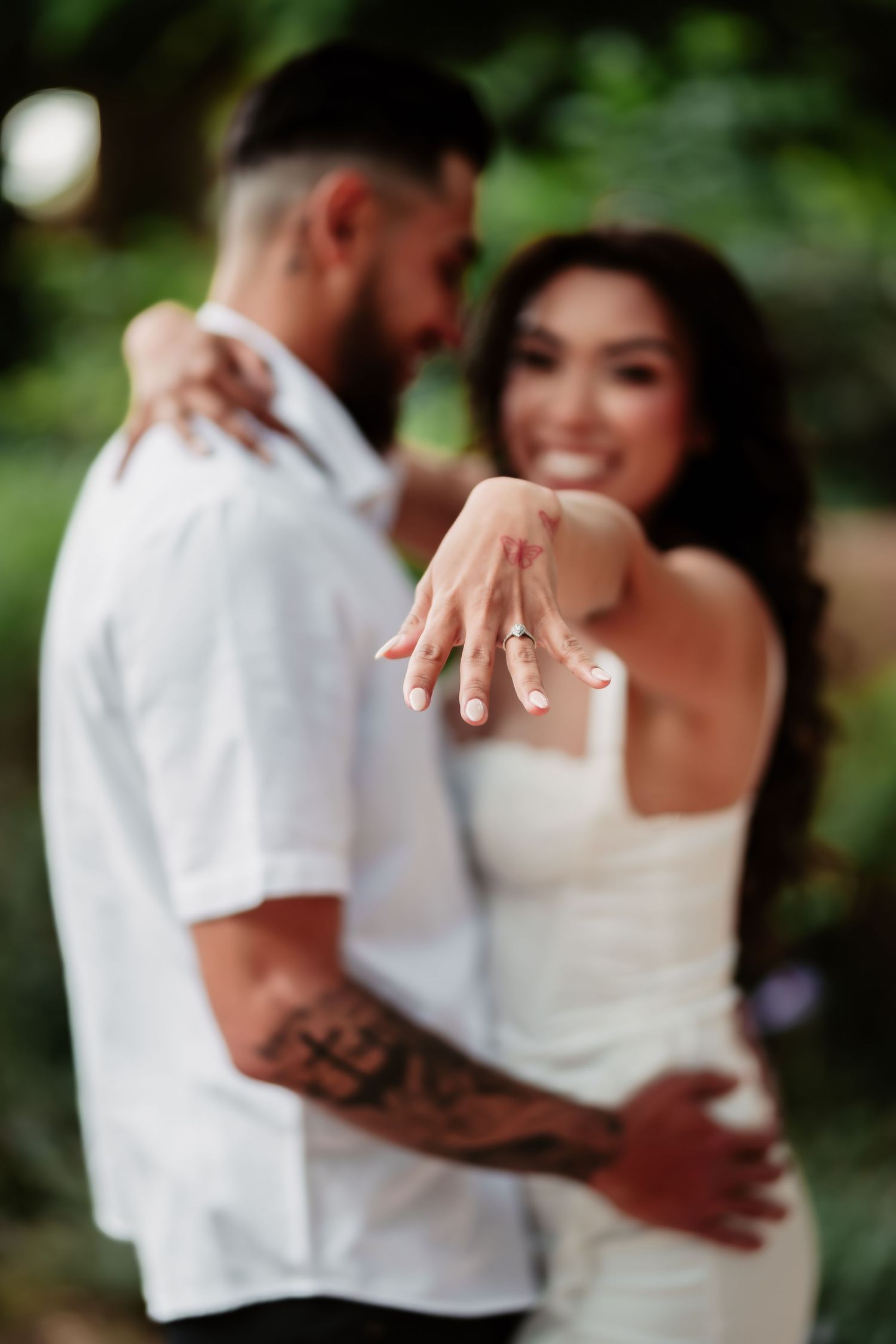 A newly engaged couple showing off the engagement ring with a blurred garden background.