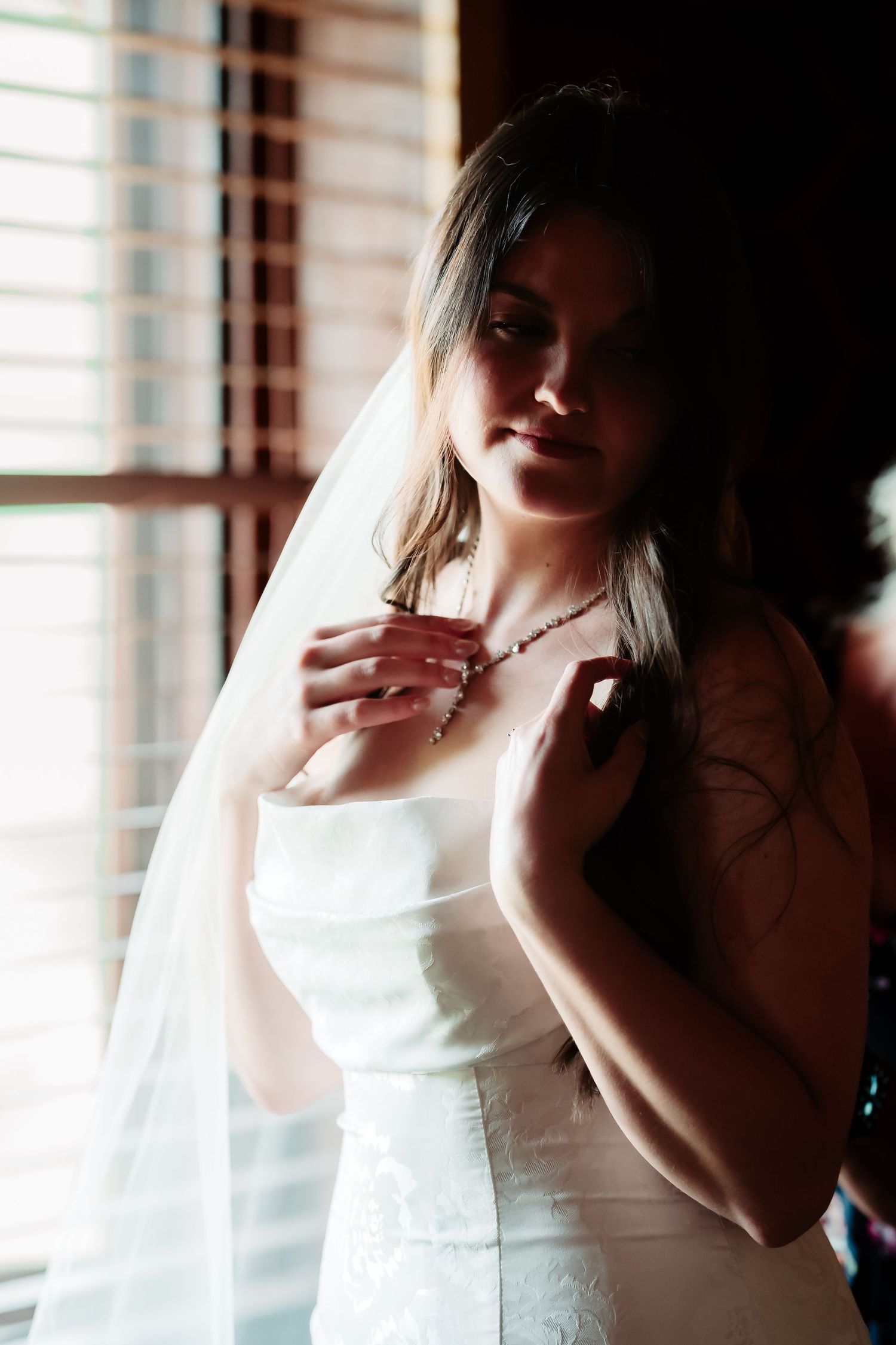 Ethereal bridal portrait with soft window light highlighting a white wedding dress.