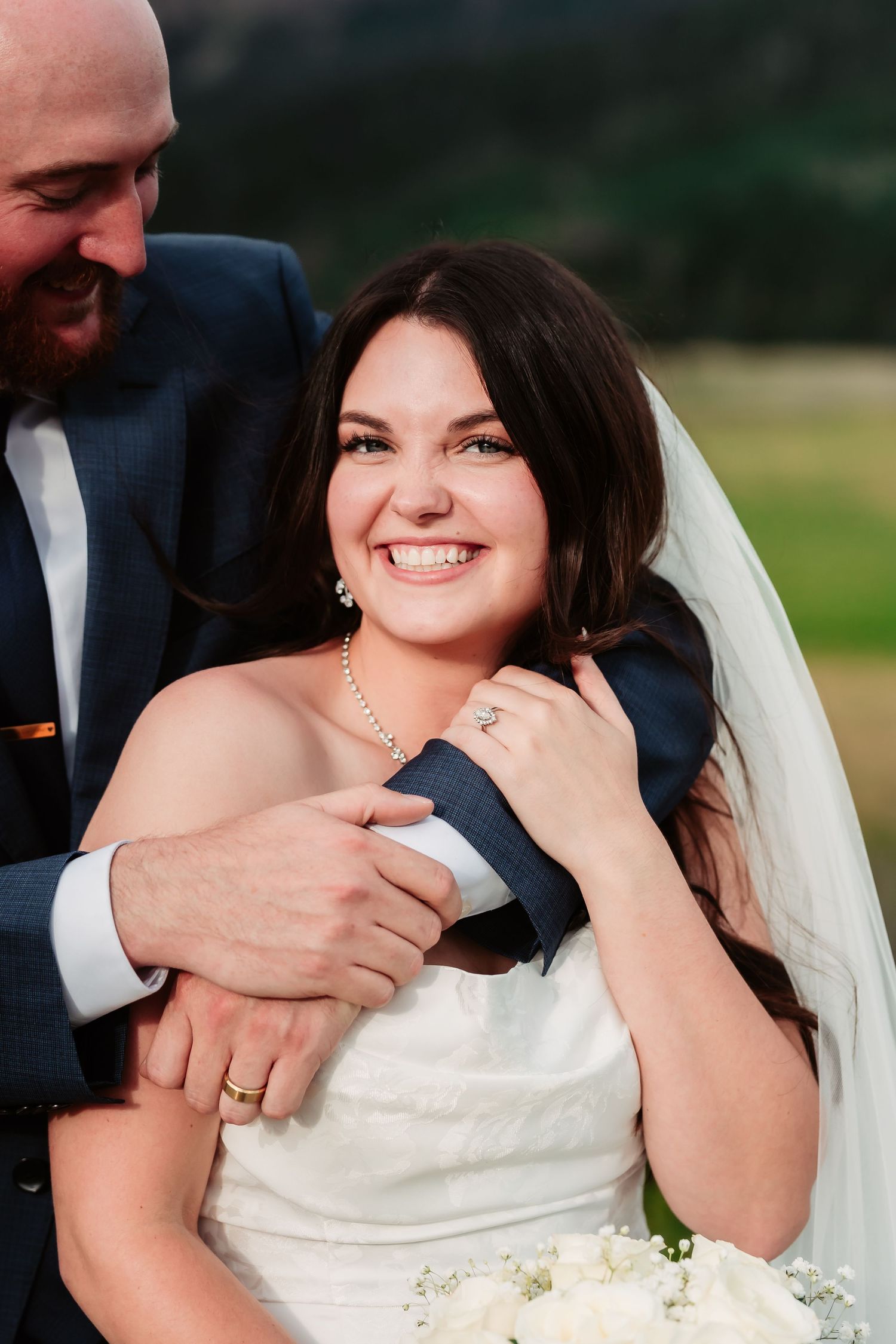 Bride and groom share joyful laughter during outdoor wedding portraits.