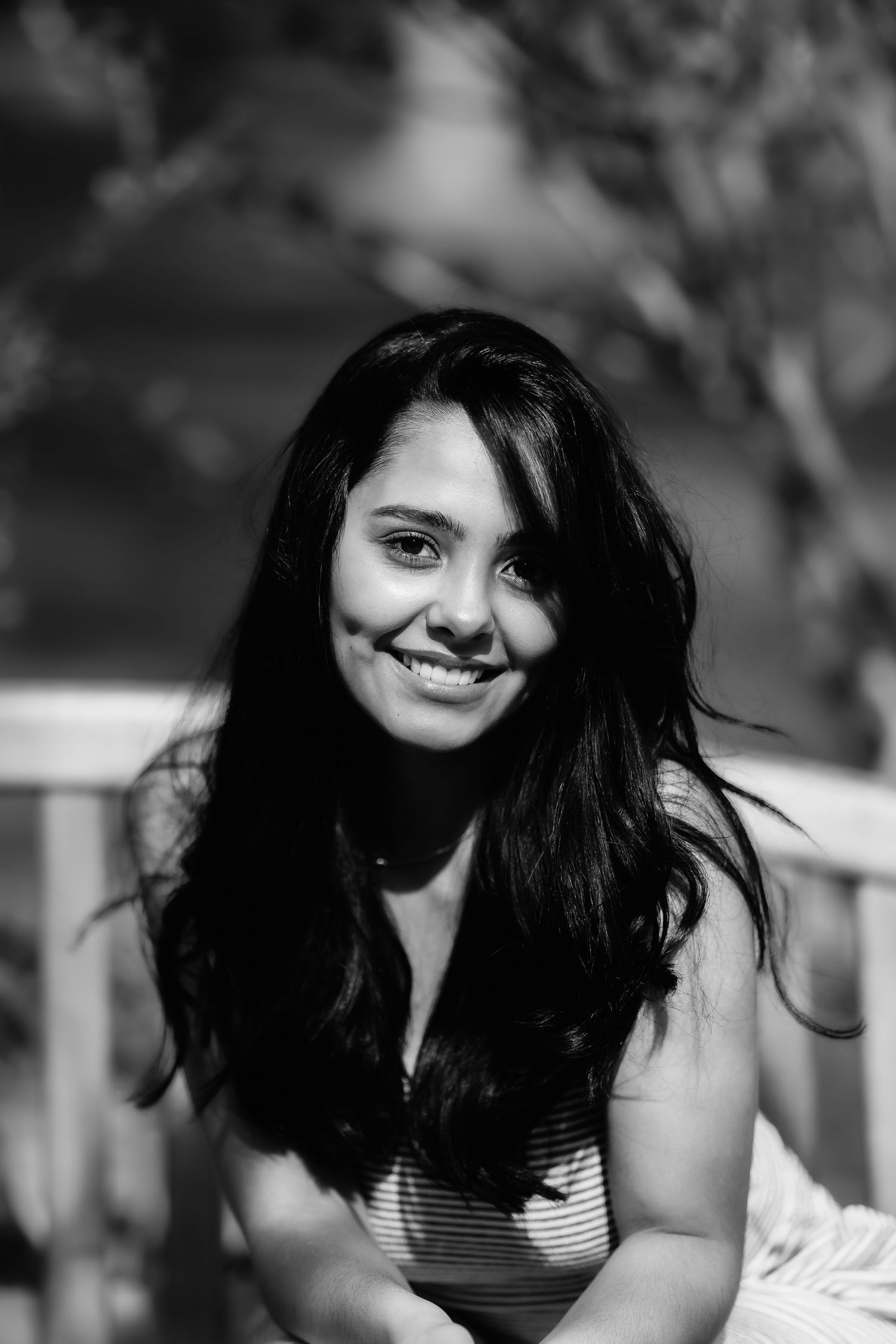 Black and white close-up portrait of a woman with flowing dark hair and bright smile.