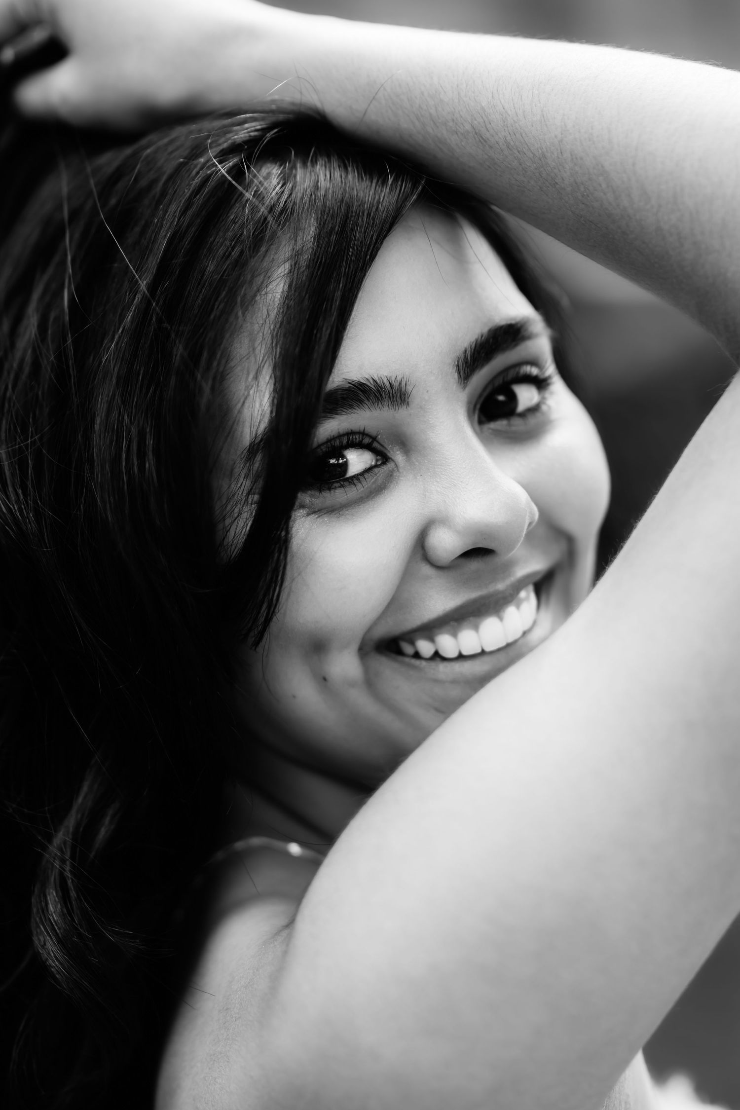 A black and white portrait capturing a bright smile and playful pose.