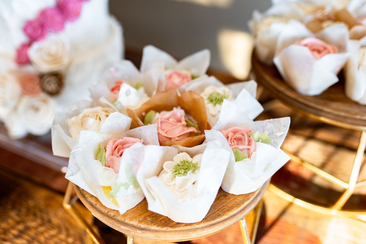 Delicate pink and white floral decorated desserts displayed on tiered serving plates.