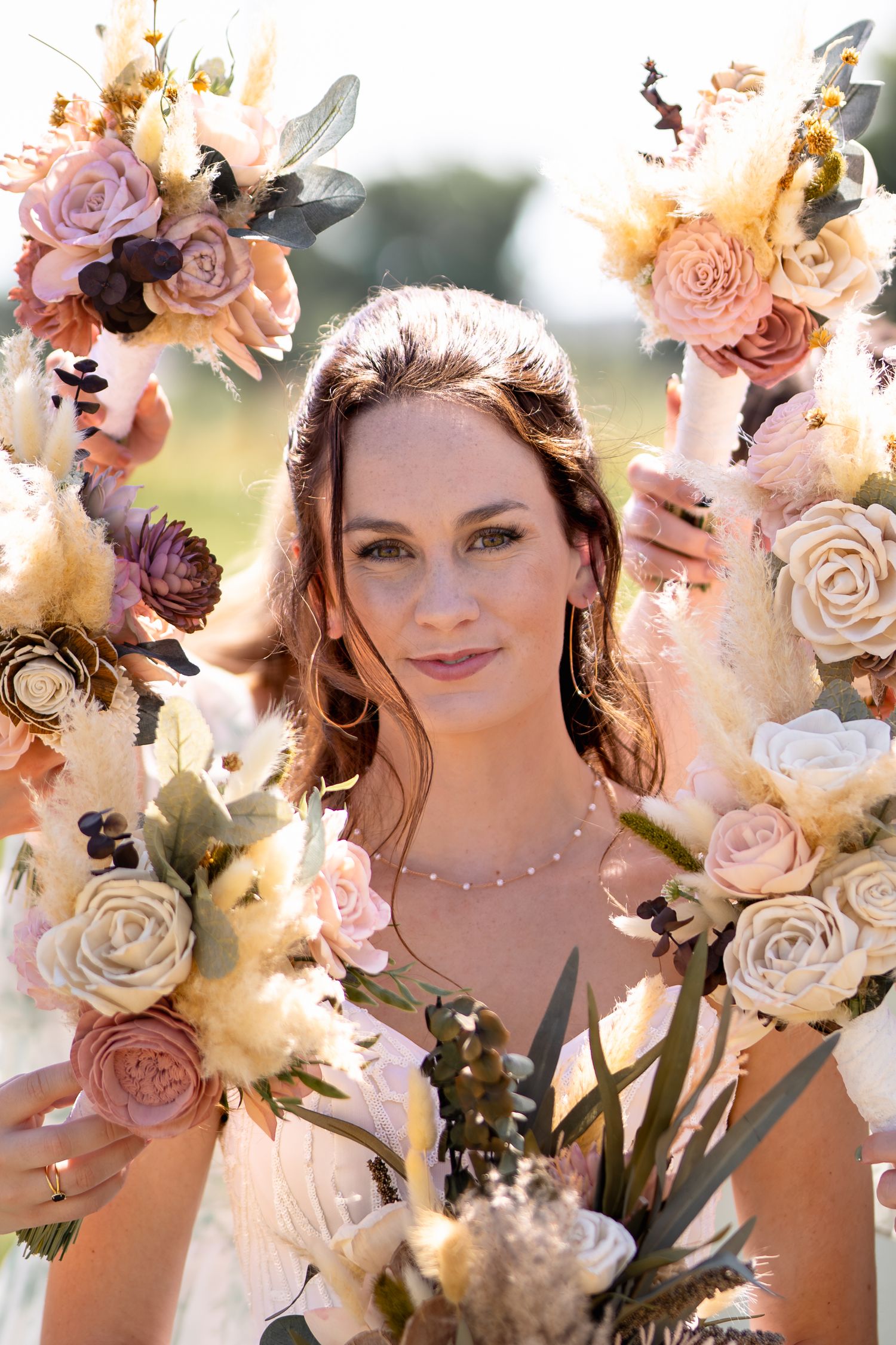 Beautiful floral arch with blush and cream roses frames romantic bridal portrait in natural light.