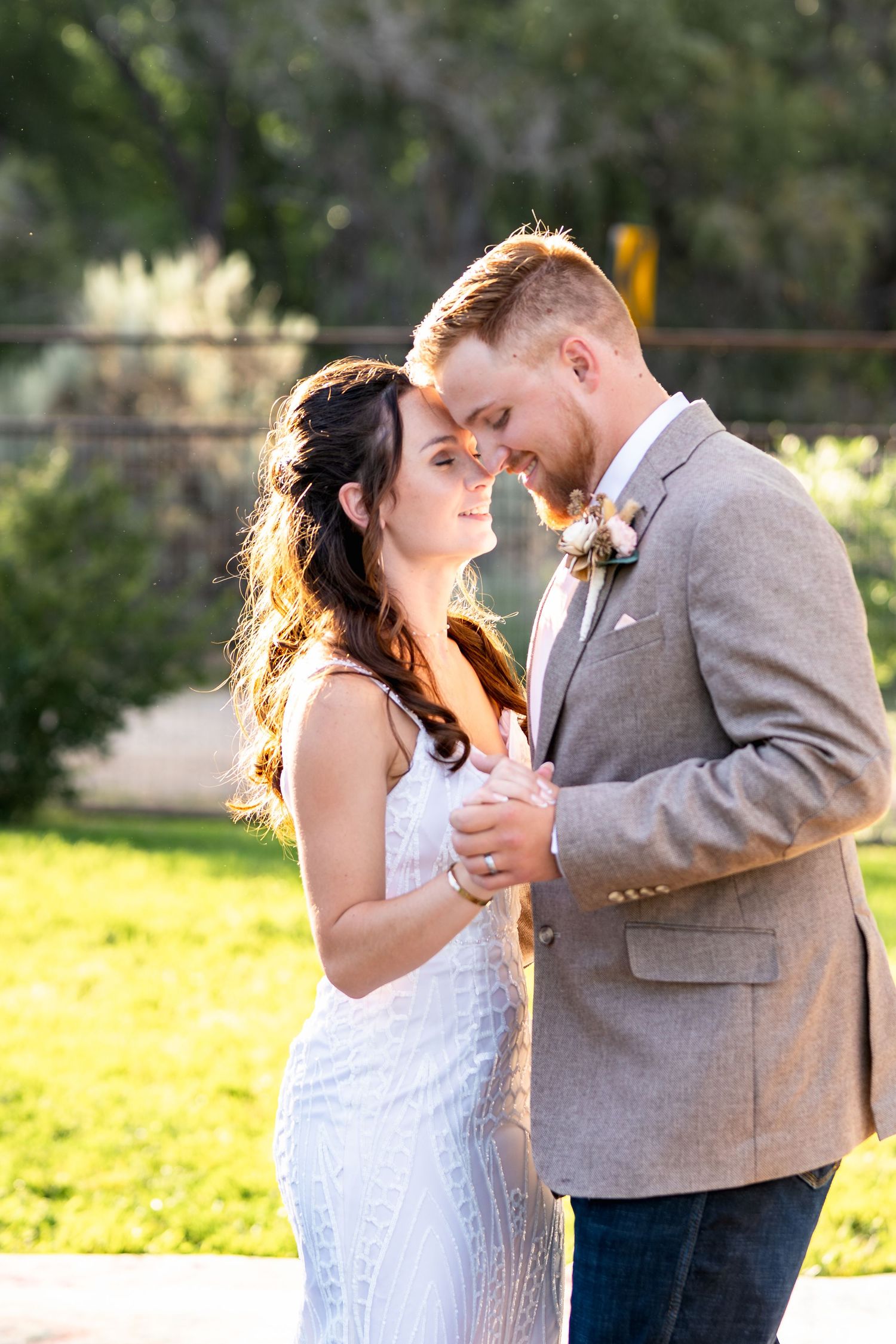 A romantic moment between newlyweds at sunset in an outdoor garden setting.