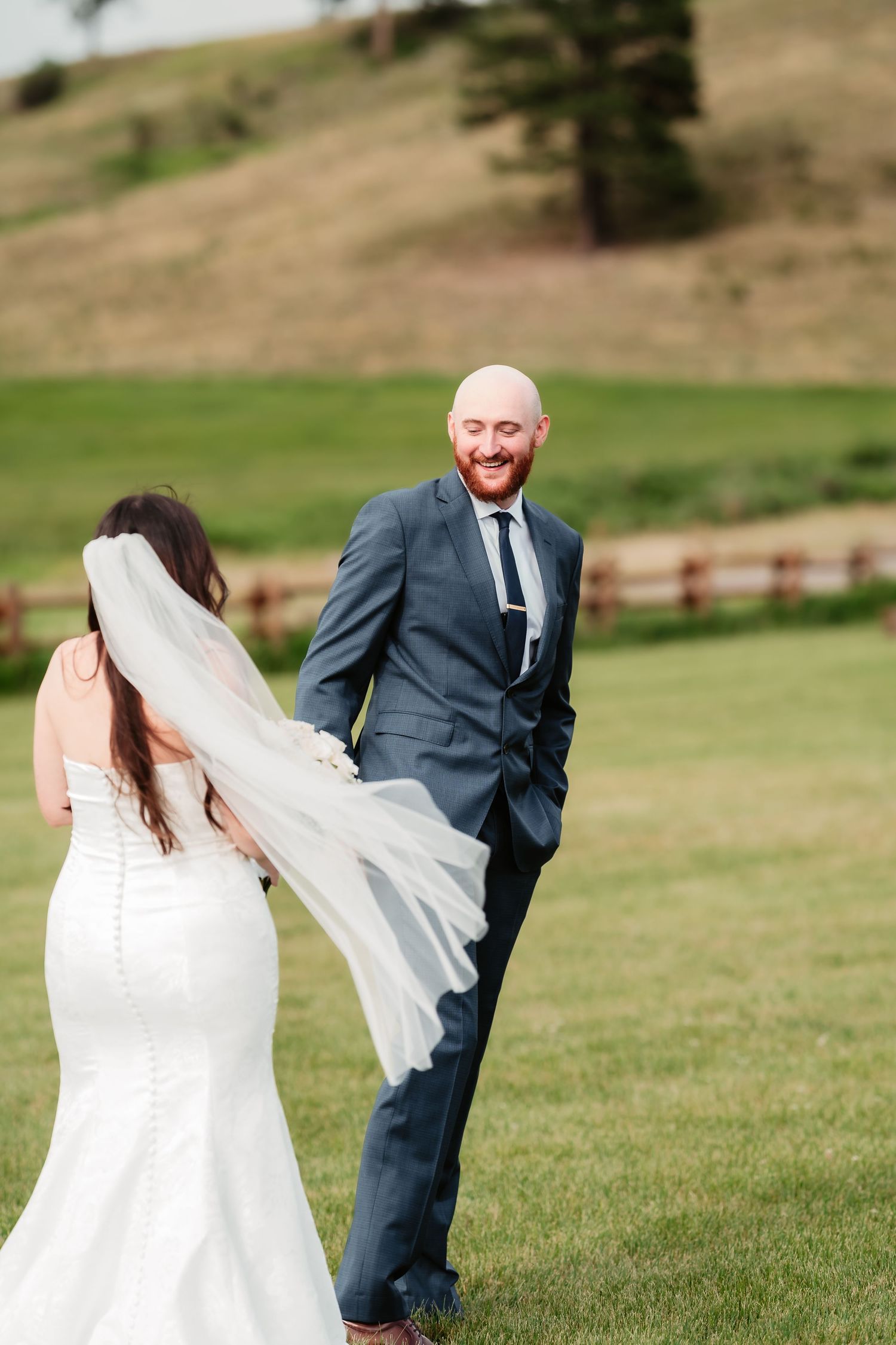 Newlyweds share a moment in a beautiful mountain setting with rustic fencing.