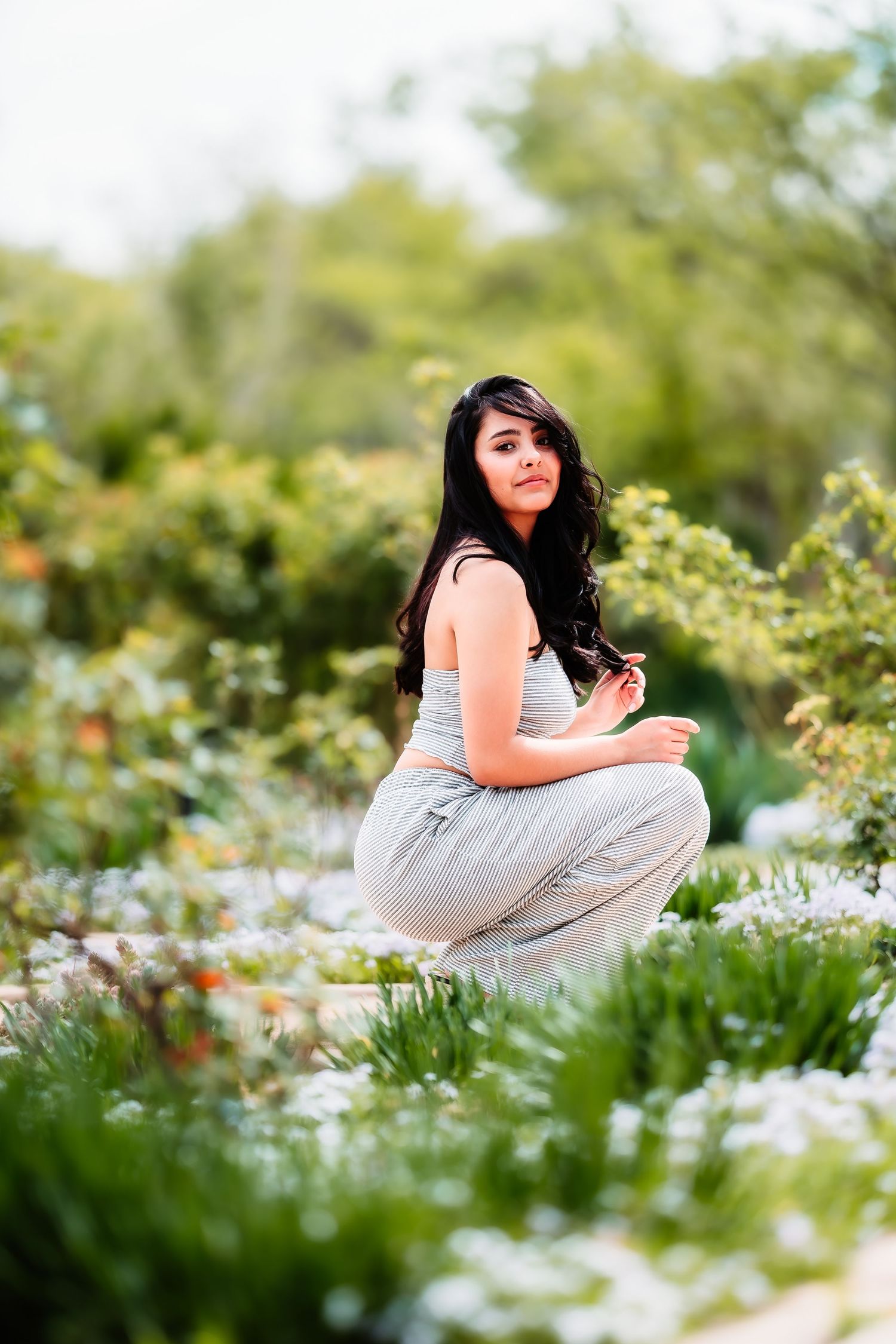 A lifestyle portrait in a garden setting with blooming white flowers and greenery.