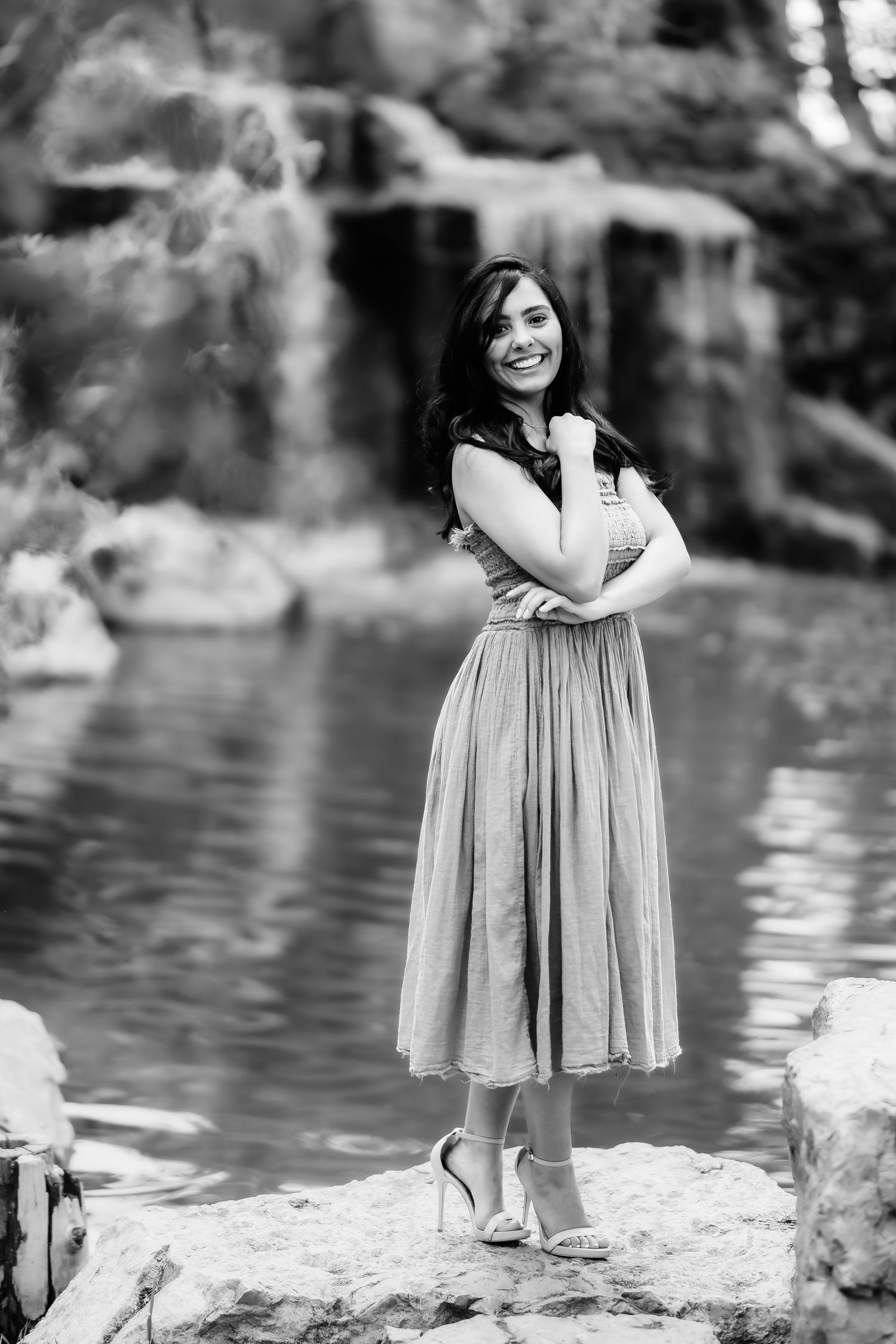 Beautiful black and white portrait captured by a serene pond with waterfall backdrop.