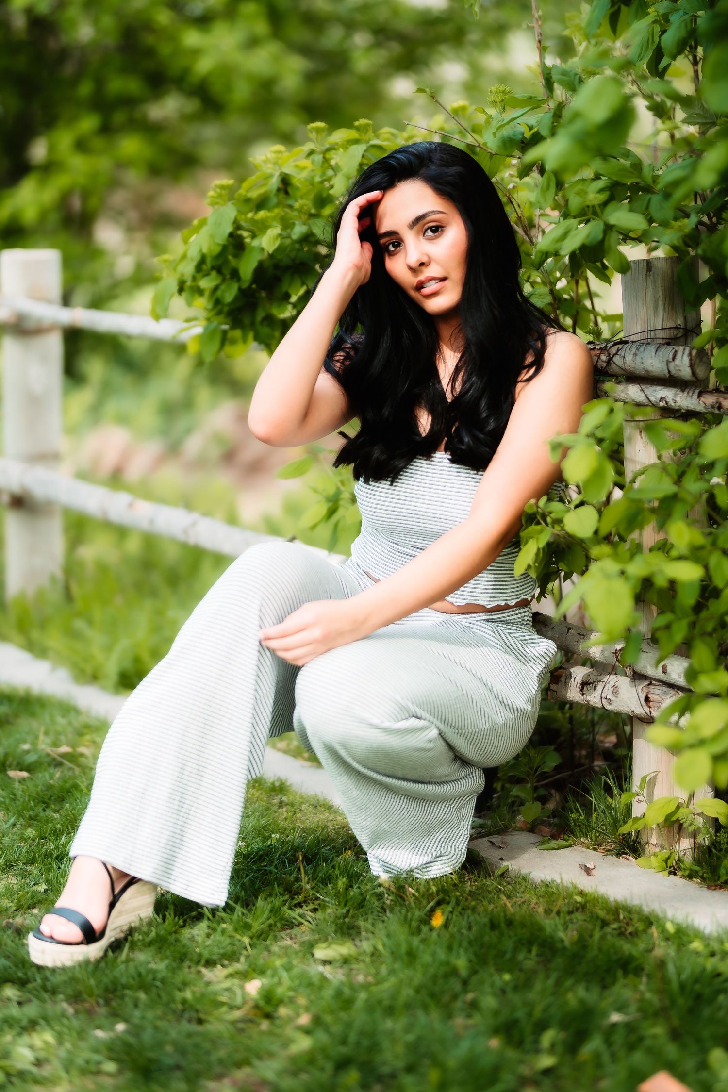 Summer garden portrait with white fence and green foliage backdrop.