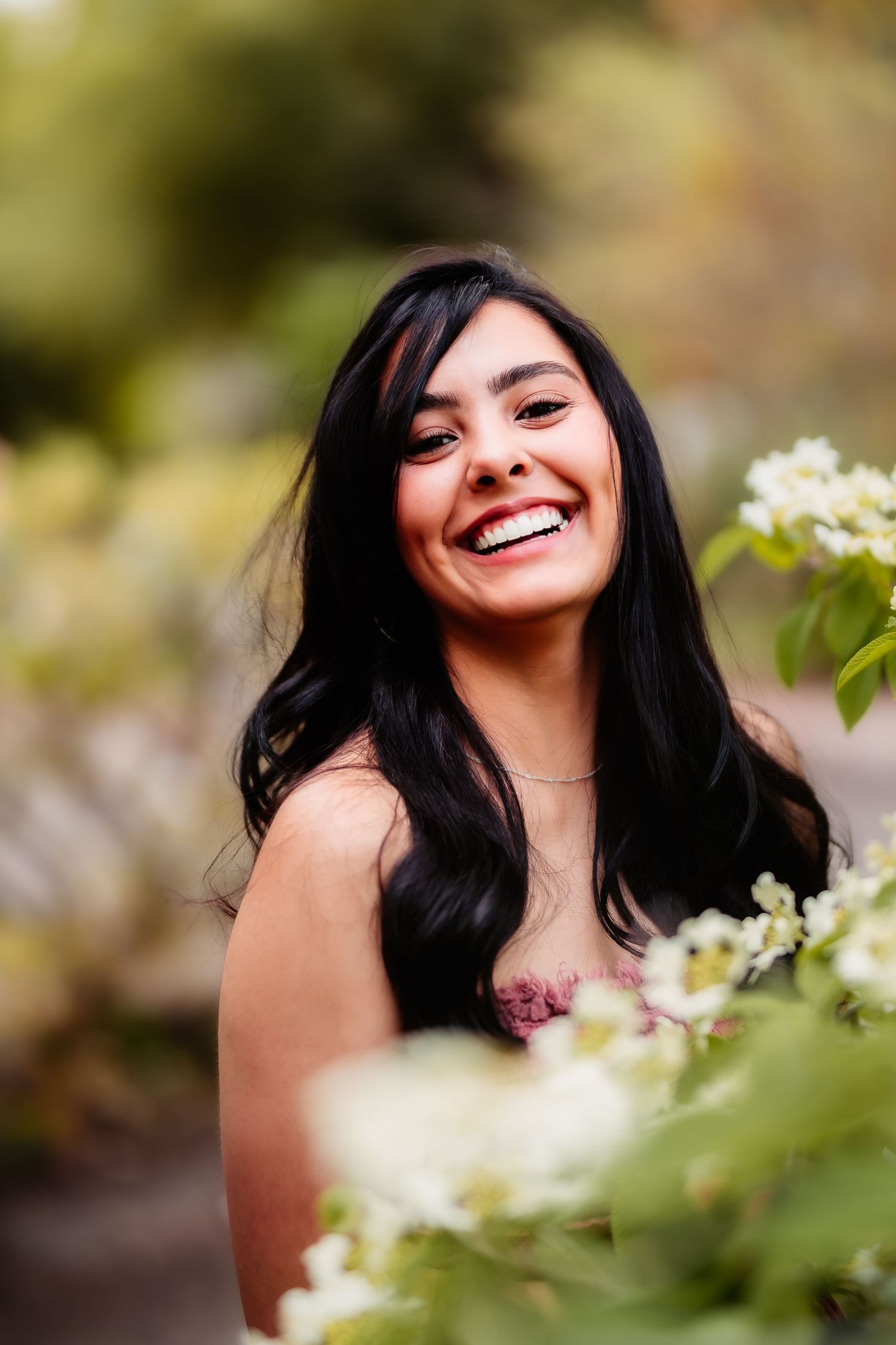 A joyful portrait amid white spring blossoms showing natural radiance and warmth.