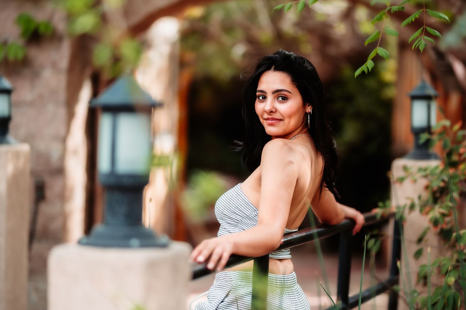 Portrait of someone in casual attire posing near outdoor lanterns and architecture.
