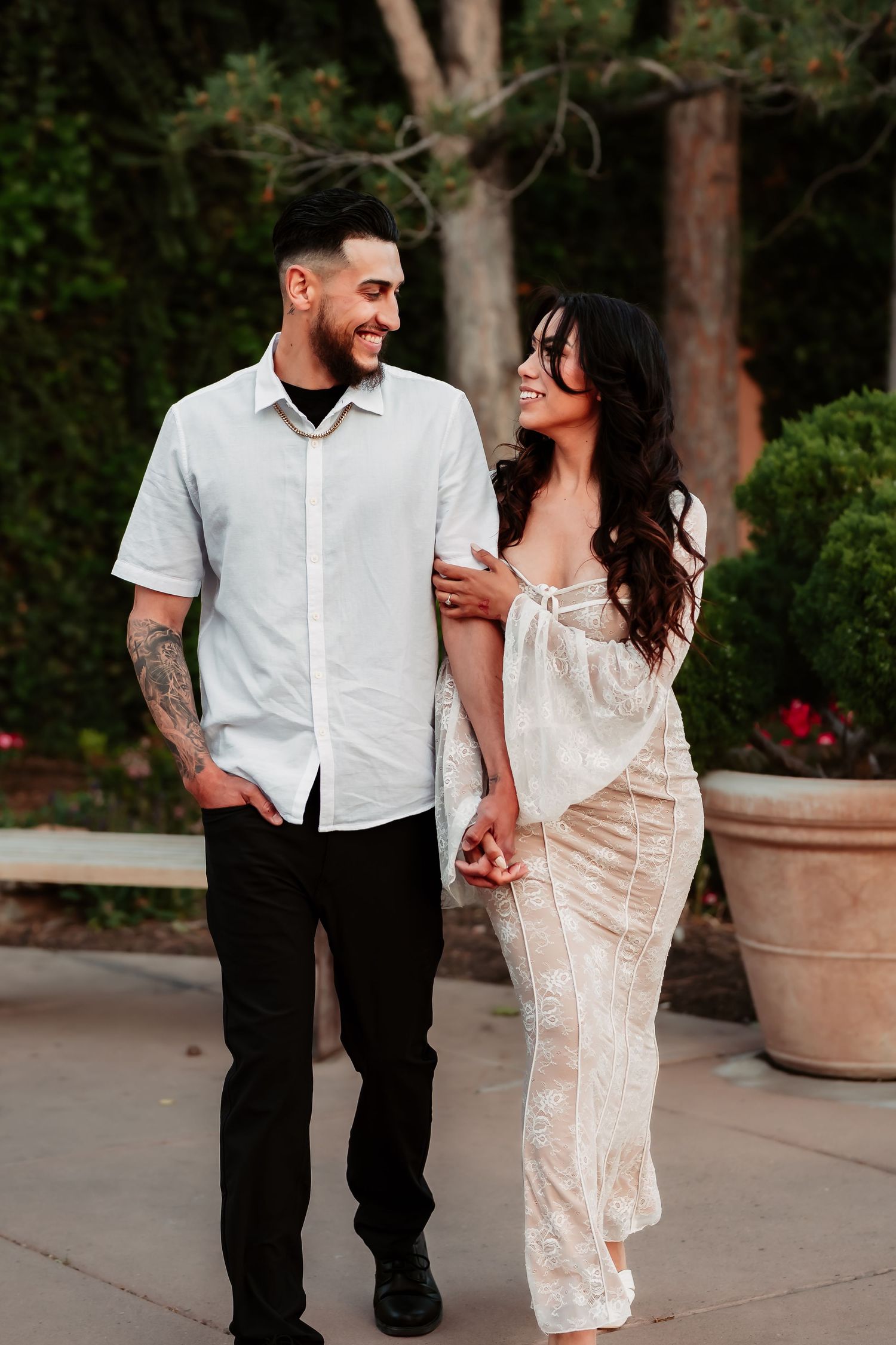 Couple shares joyful moment while walking on outdoor path with garden scenery.