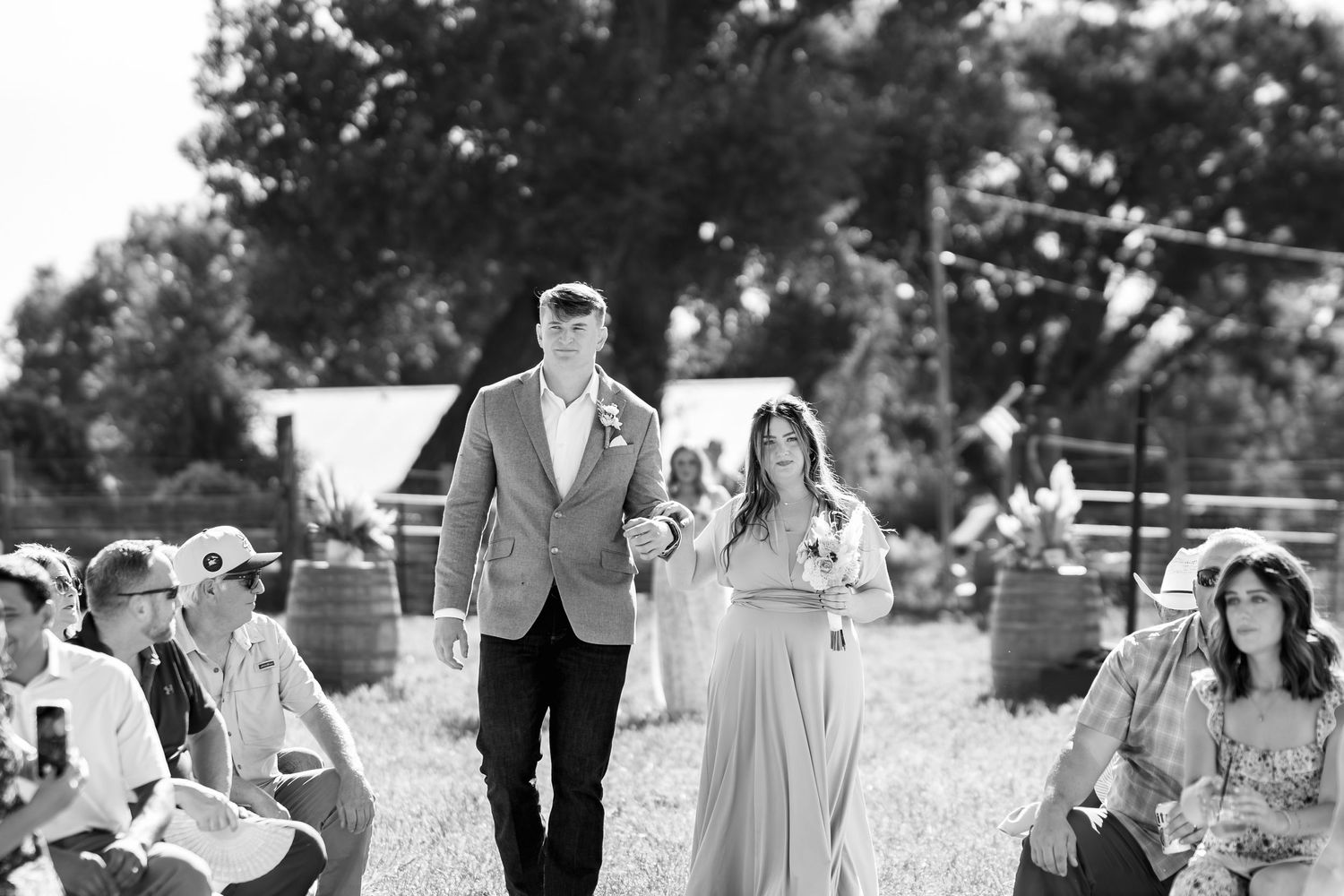 Black and white photo of a processional walk during an outdoor wedding ceremony.
