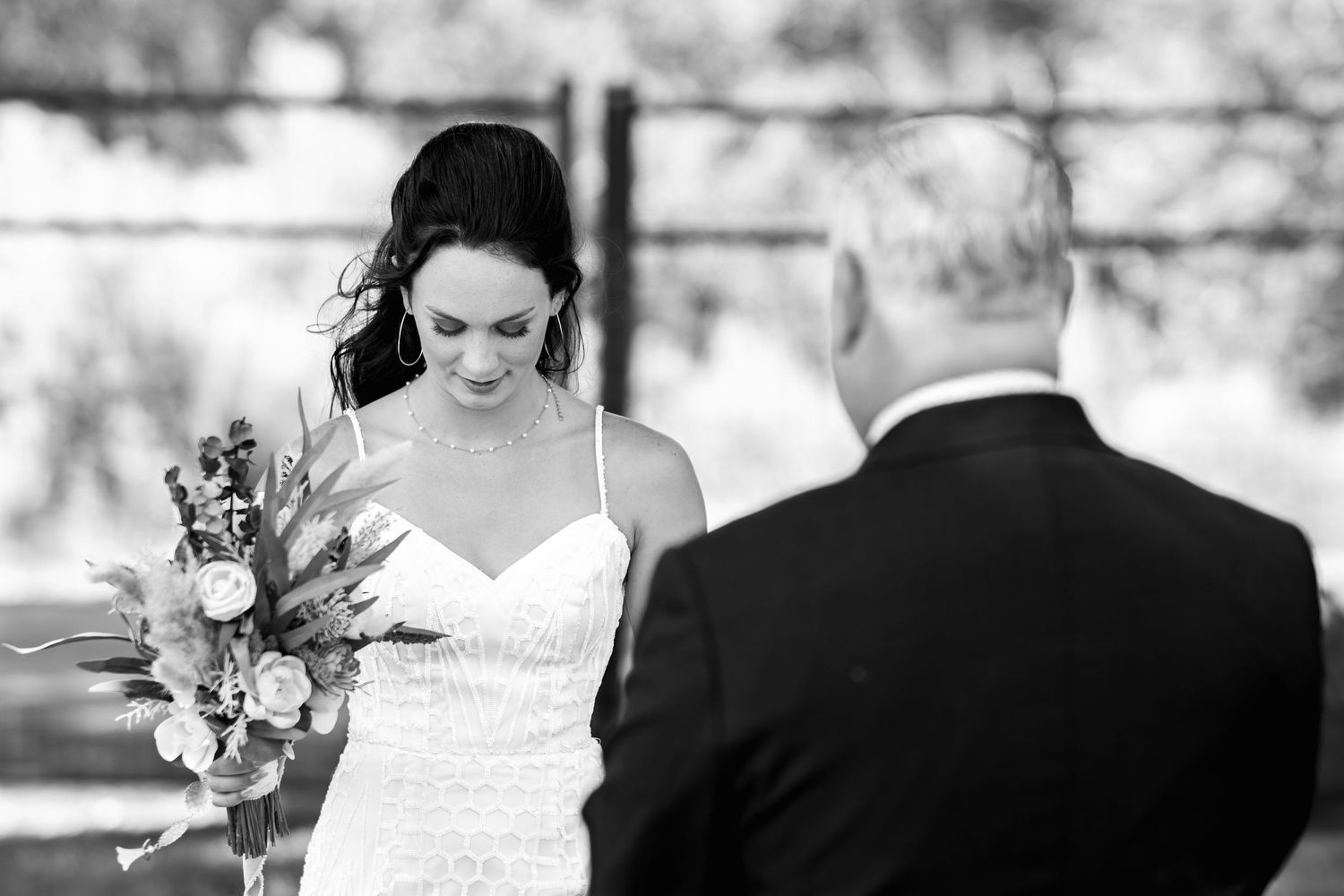 A black and white wedding portrait showing a bride holding a floral bouquet during an intimate moment.