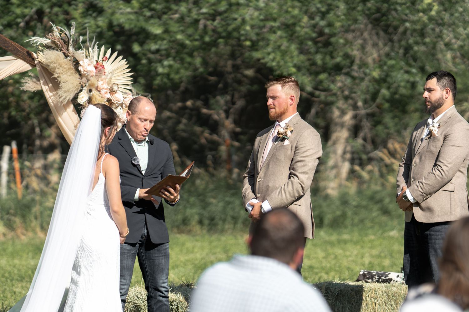 Outdoor wedding ceremony in progress with the couple and officiant surrounded by natural greenery.