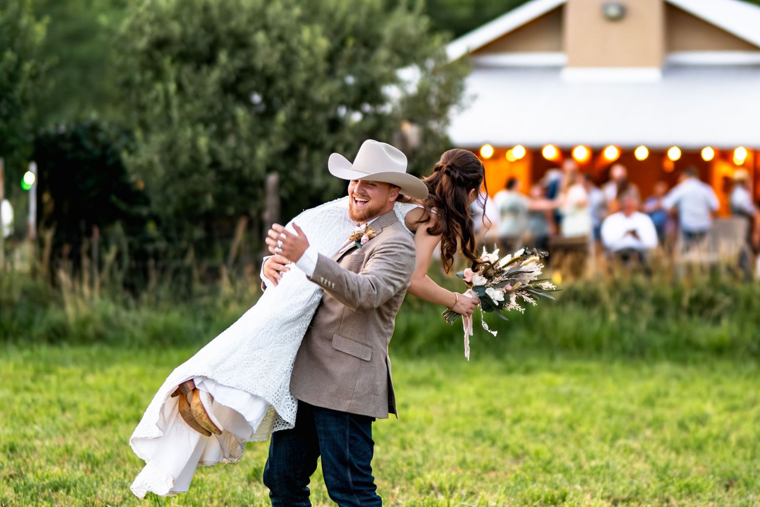 Joyful couple celebrates during outdoor wedding with rustic barn in background.