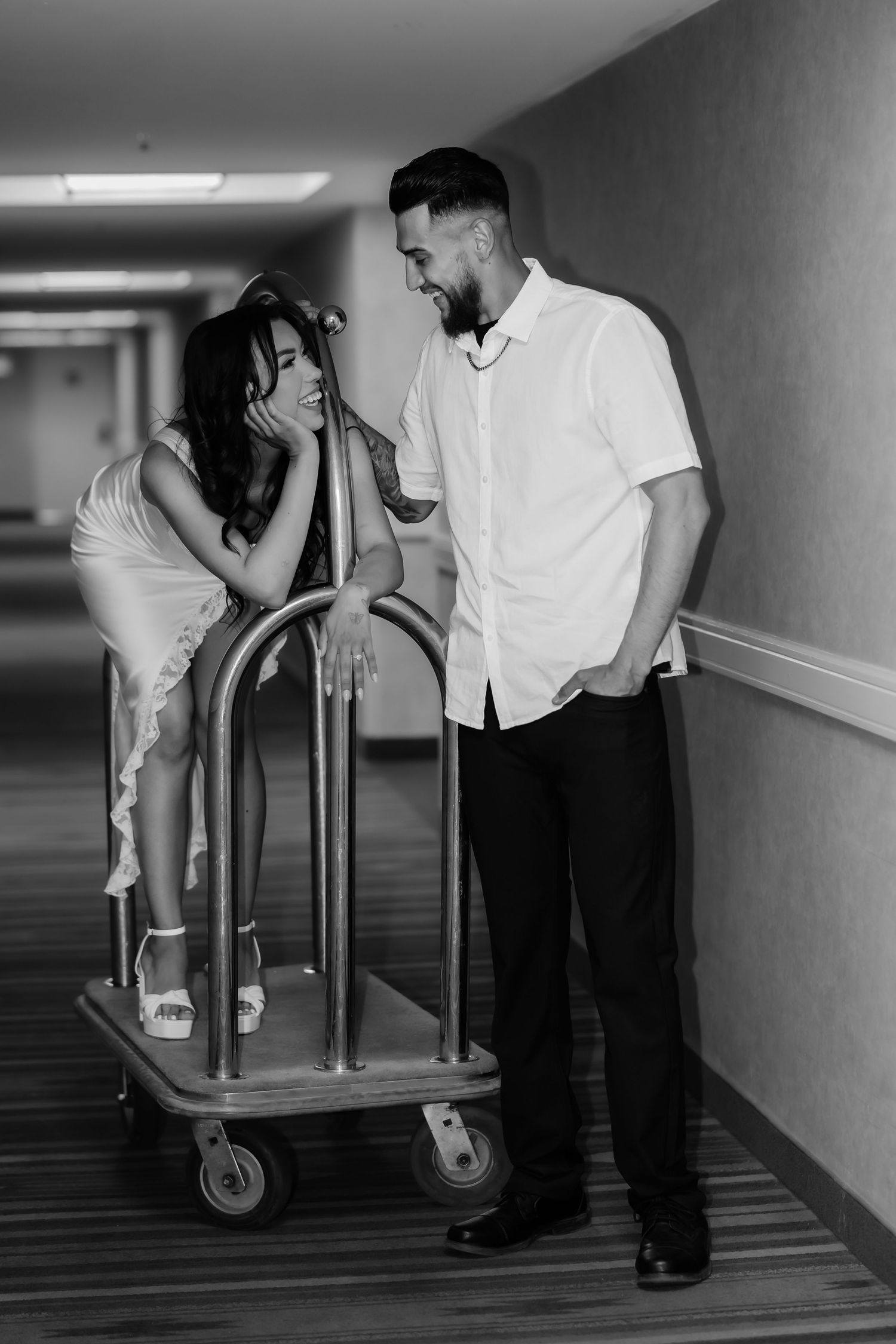 A series of black and white photos showing playful moments with a hotel luggage cart in a hallway.