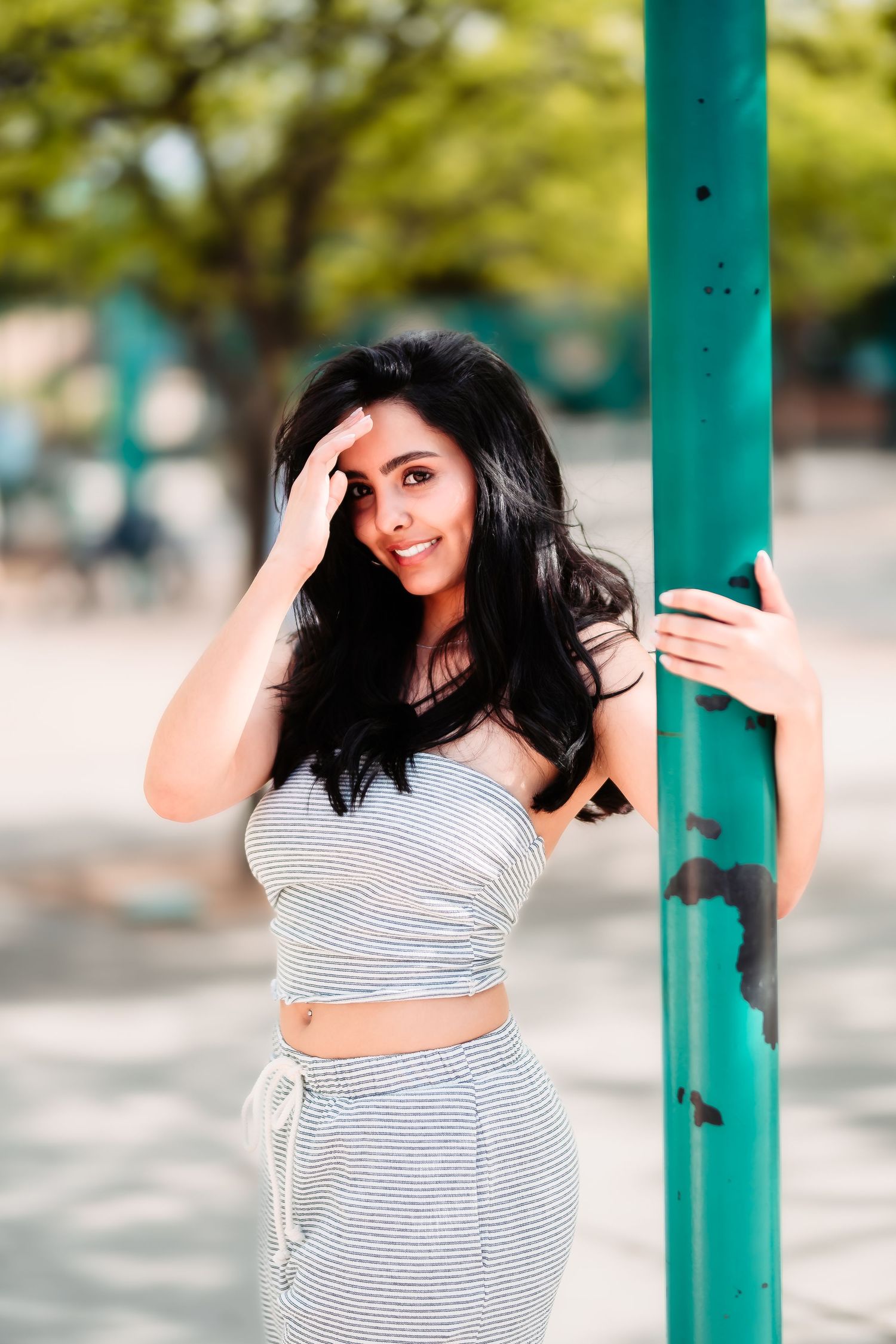 A casual outdoor portrait by a turquoise pole wearing a striped matching set.
