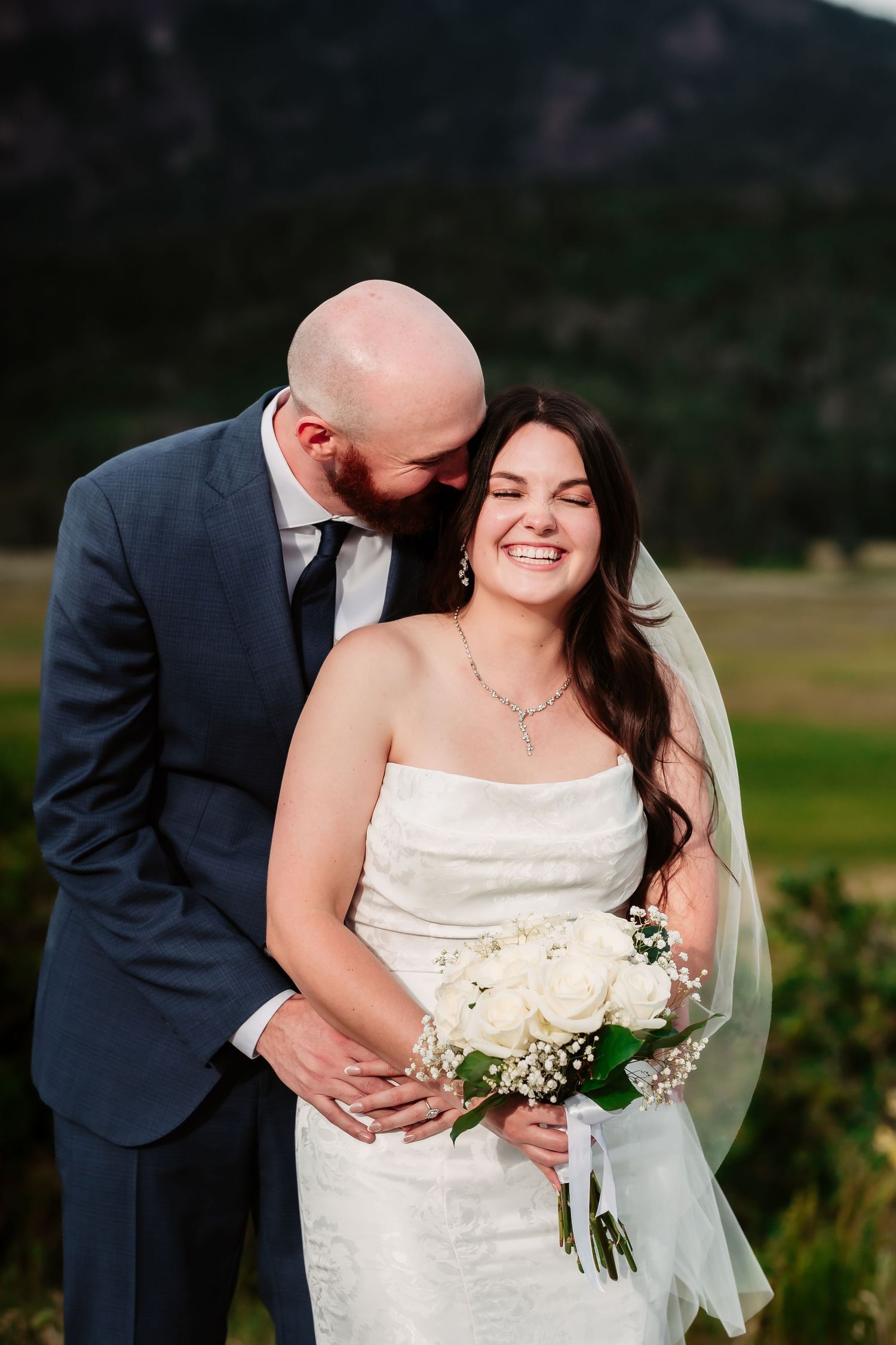 Joyful wedding couple embracing during outdoor photo session.
