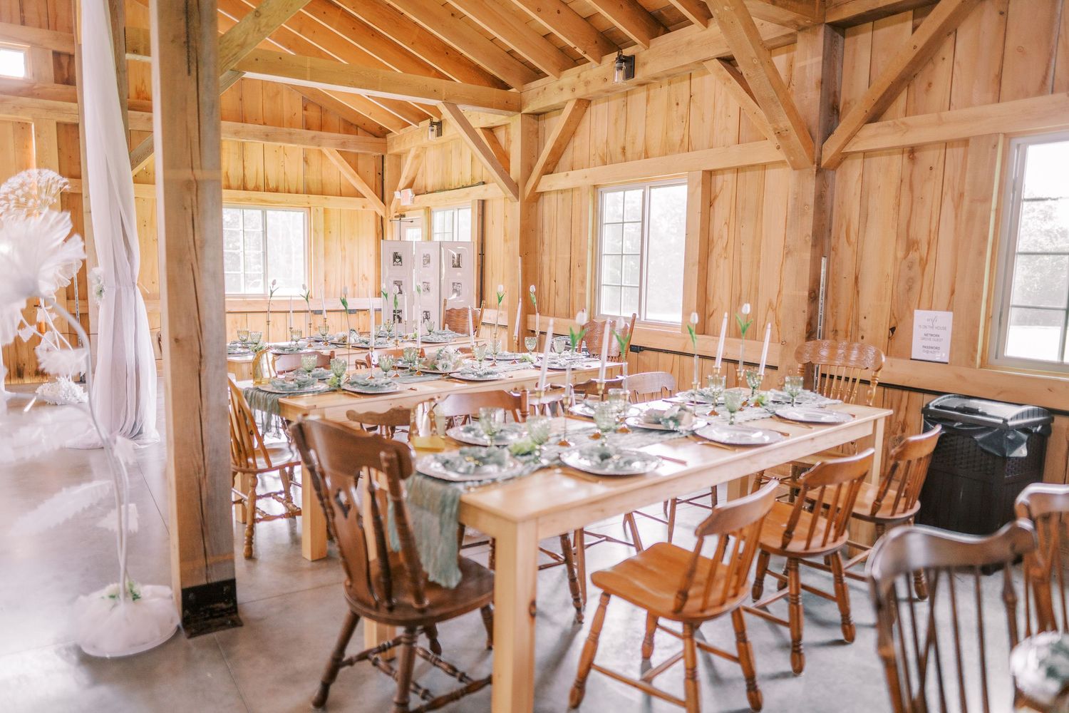 Rustic wood-paneled barn wedding venue with long tables and natural light streaming through windows.