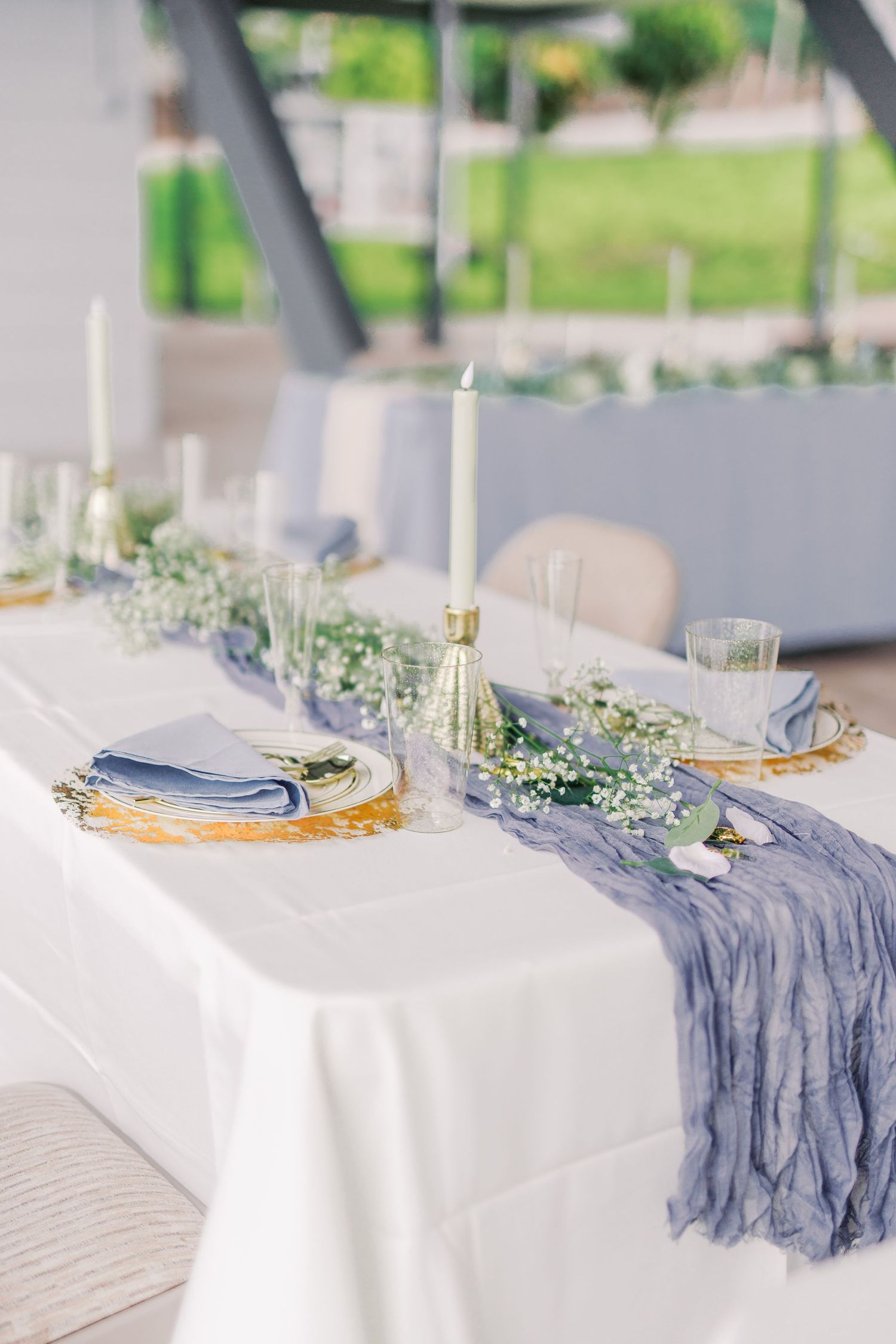 Elegant wedding table setting with white tablecloth, blue runner, and delicate floral centerpieces.