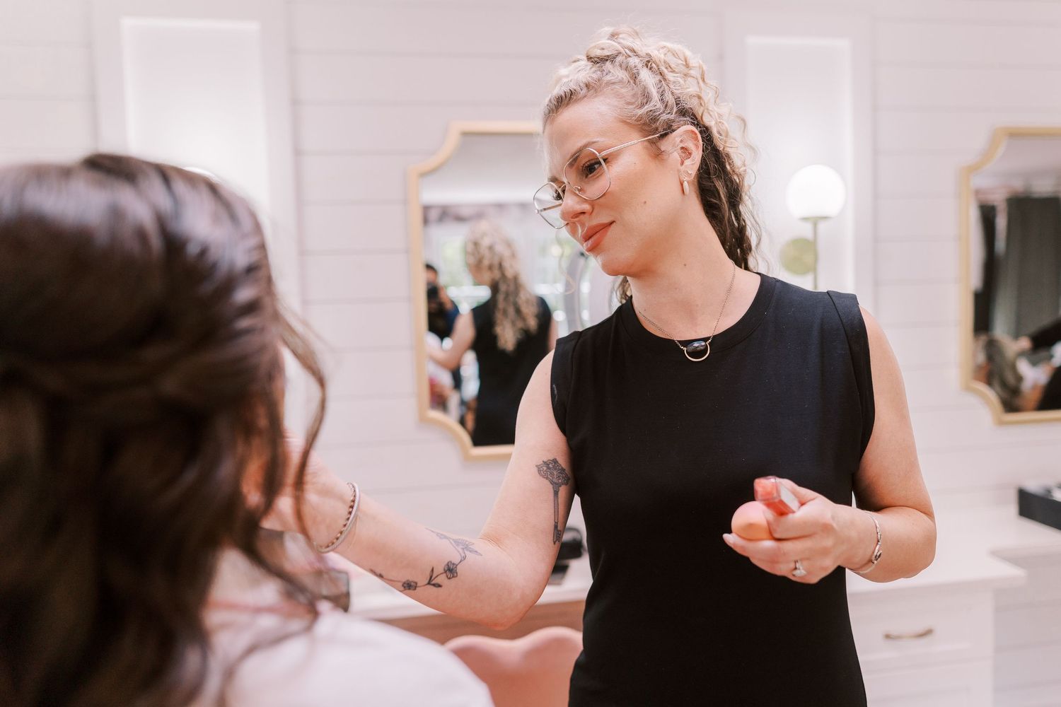 A person in a sleek black dress is getting their nails done at a beauty salon while chatting with the manicurist.