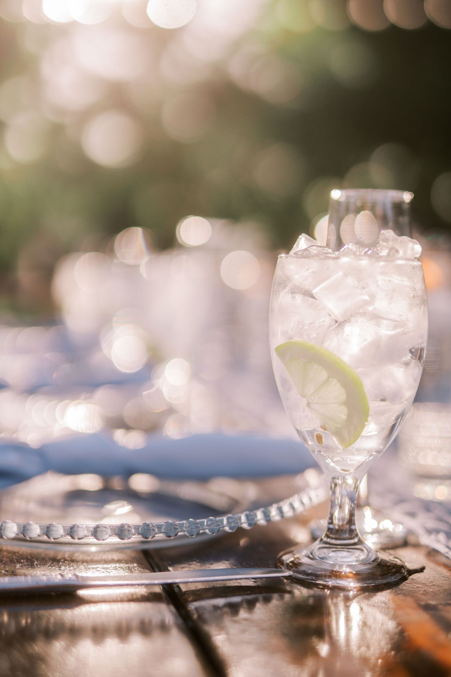 Crystal glasses with beaded plates create an elegant table setting with soft bokeh lighting in the background.