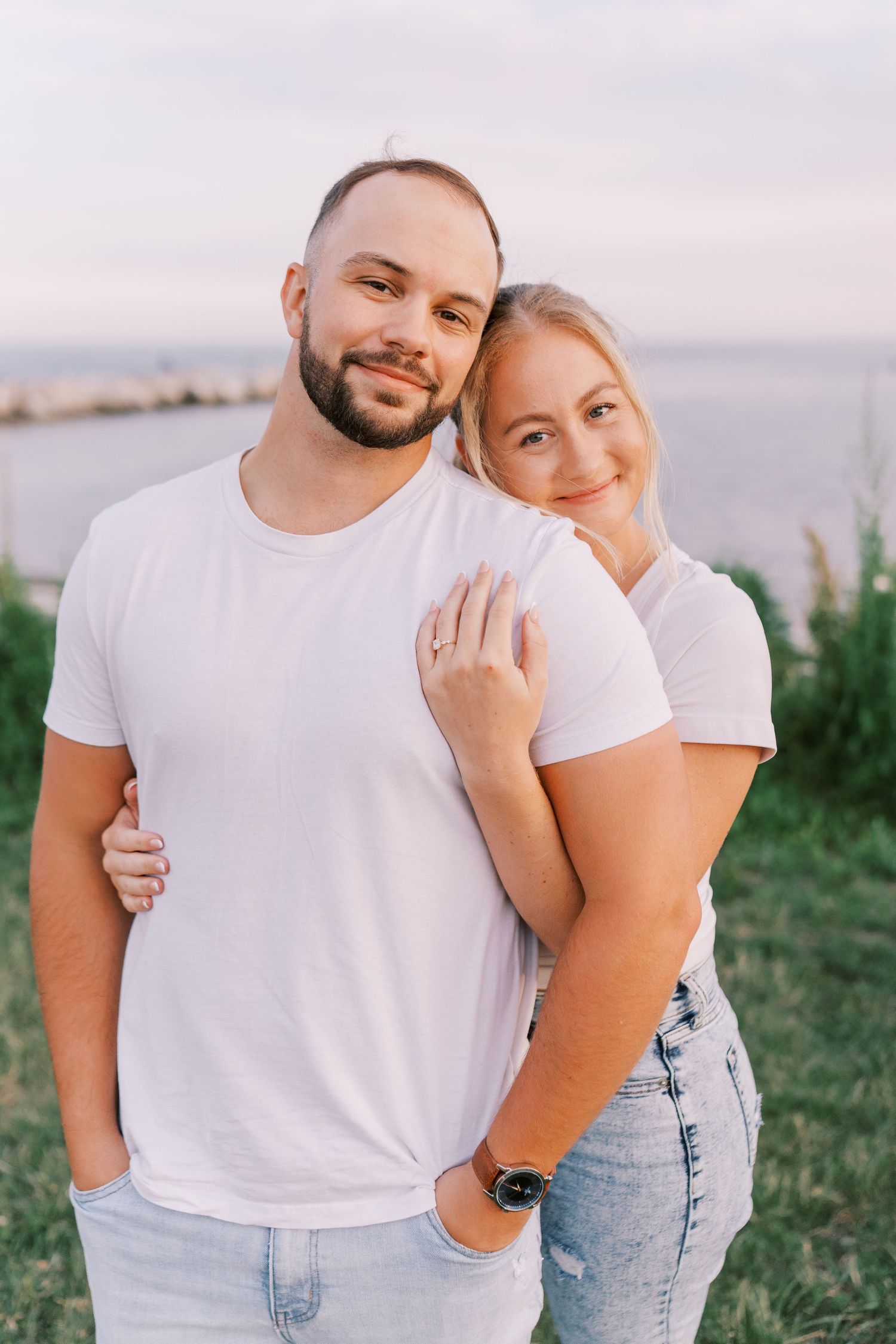 Couple in matching white t-shirts embrace outdoors in casual summer photoshoot.