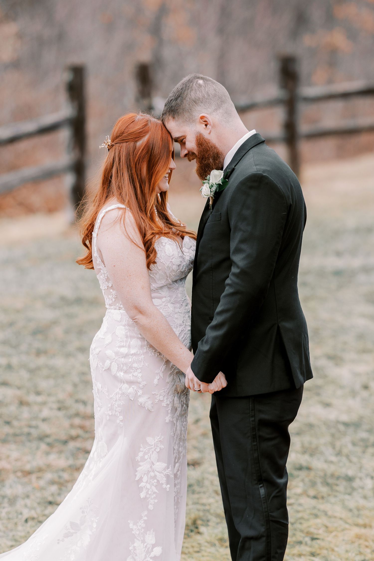 Tender moment between newlyweds in outdoor rustic setting.