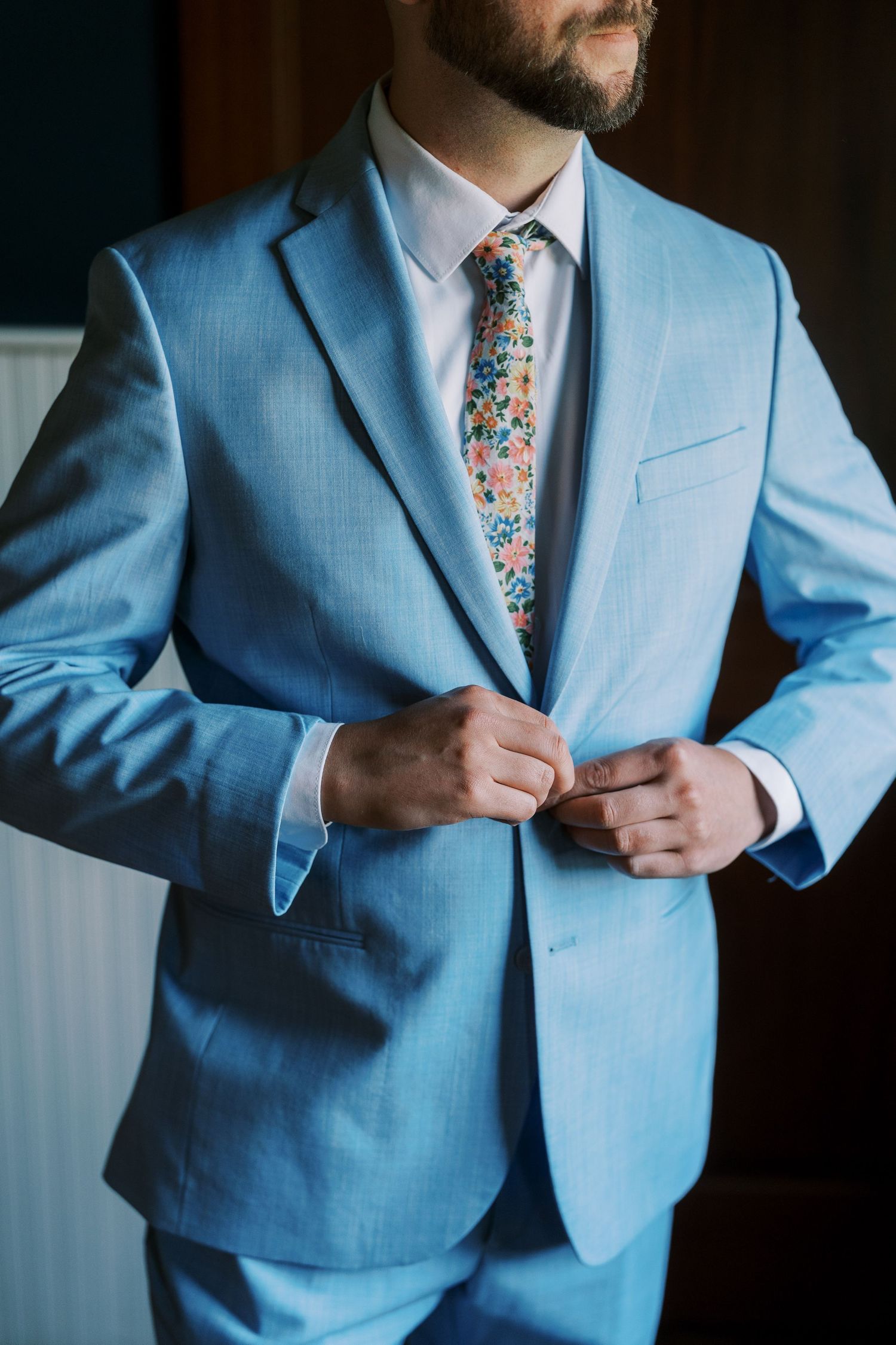 Close-up of light blue suit jacket with floral patterned tie.