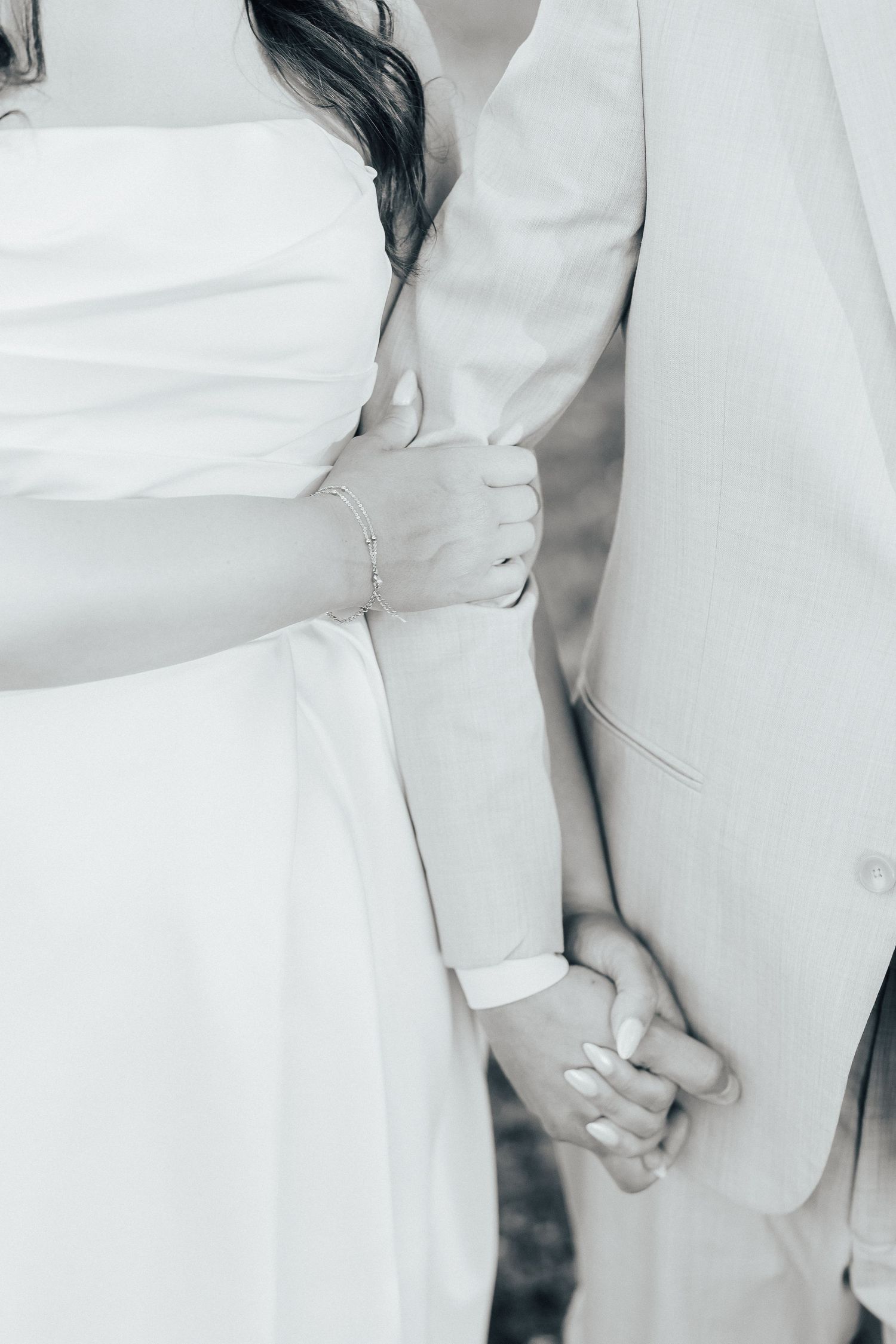 Artistic black and white photo showing details of formal white wedding attire.