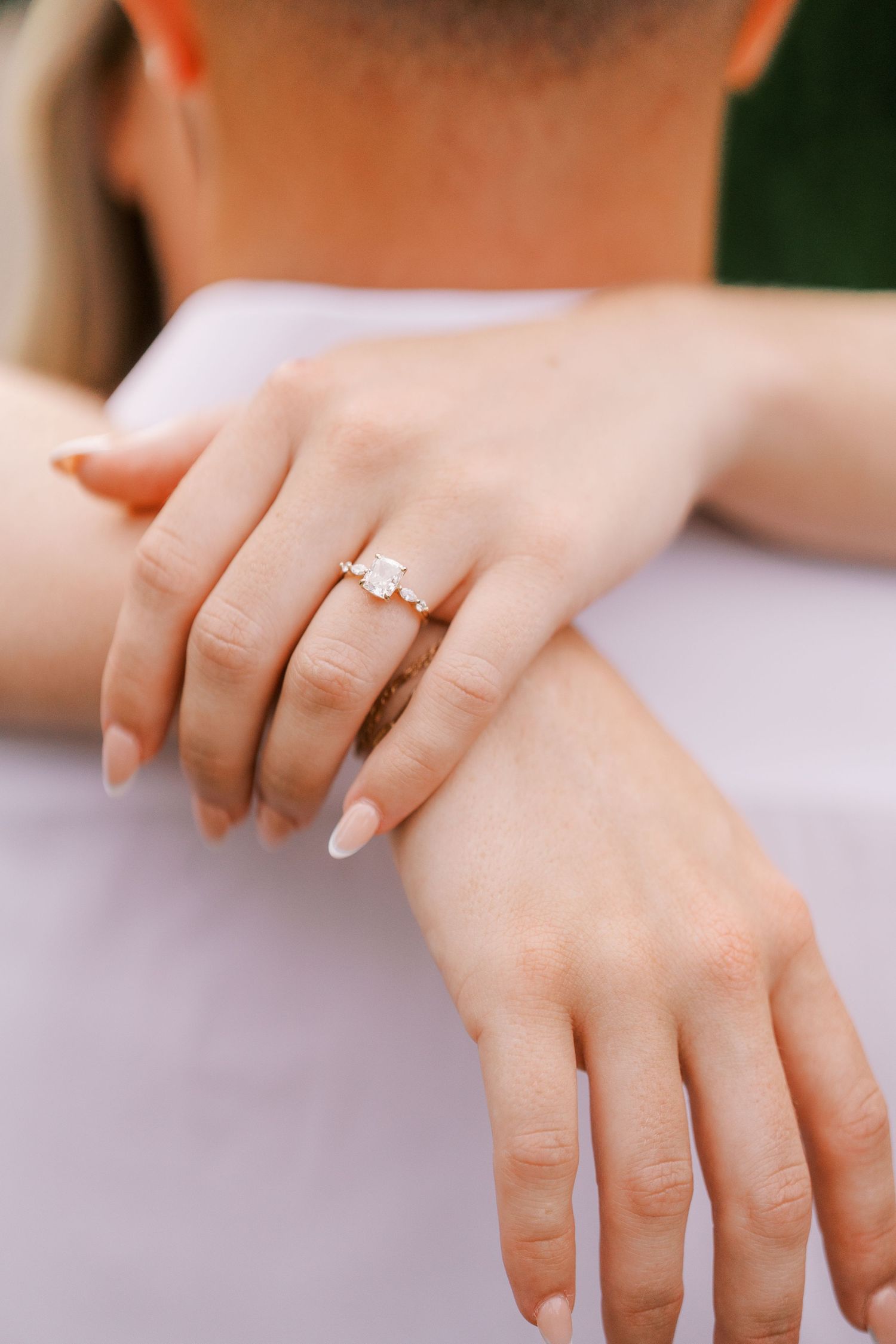 Close-up of engagement ring on hand with neutral manicured nails.