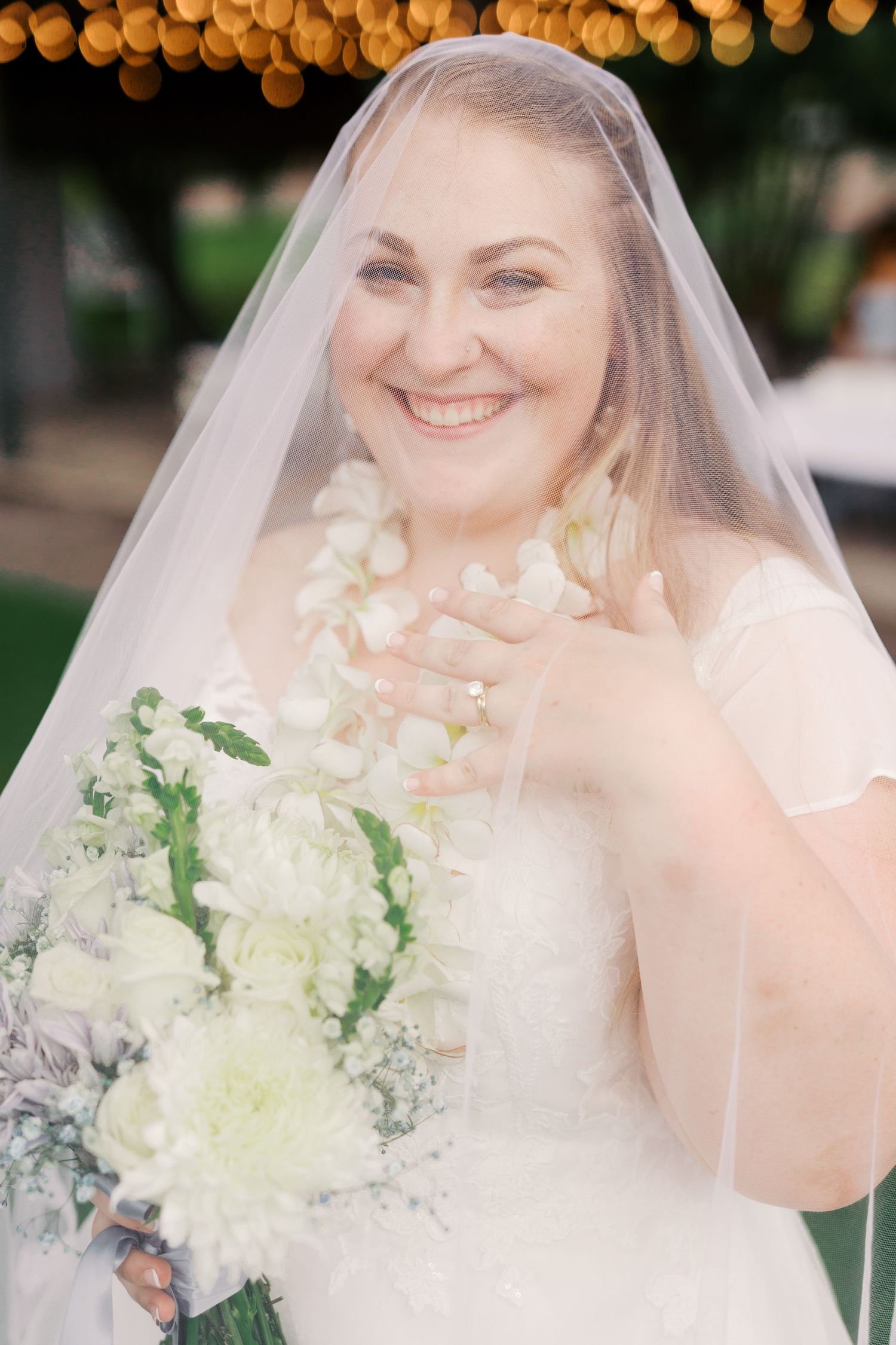 Wedding portrait of a bride wearing a veil and white dress holding a bouquet of white flowers.