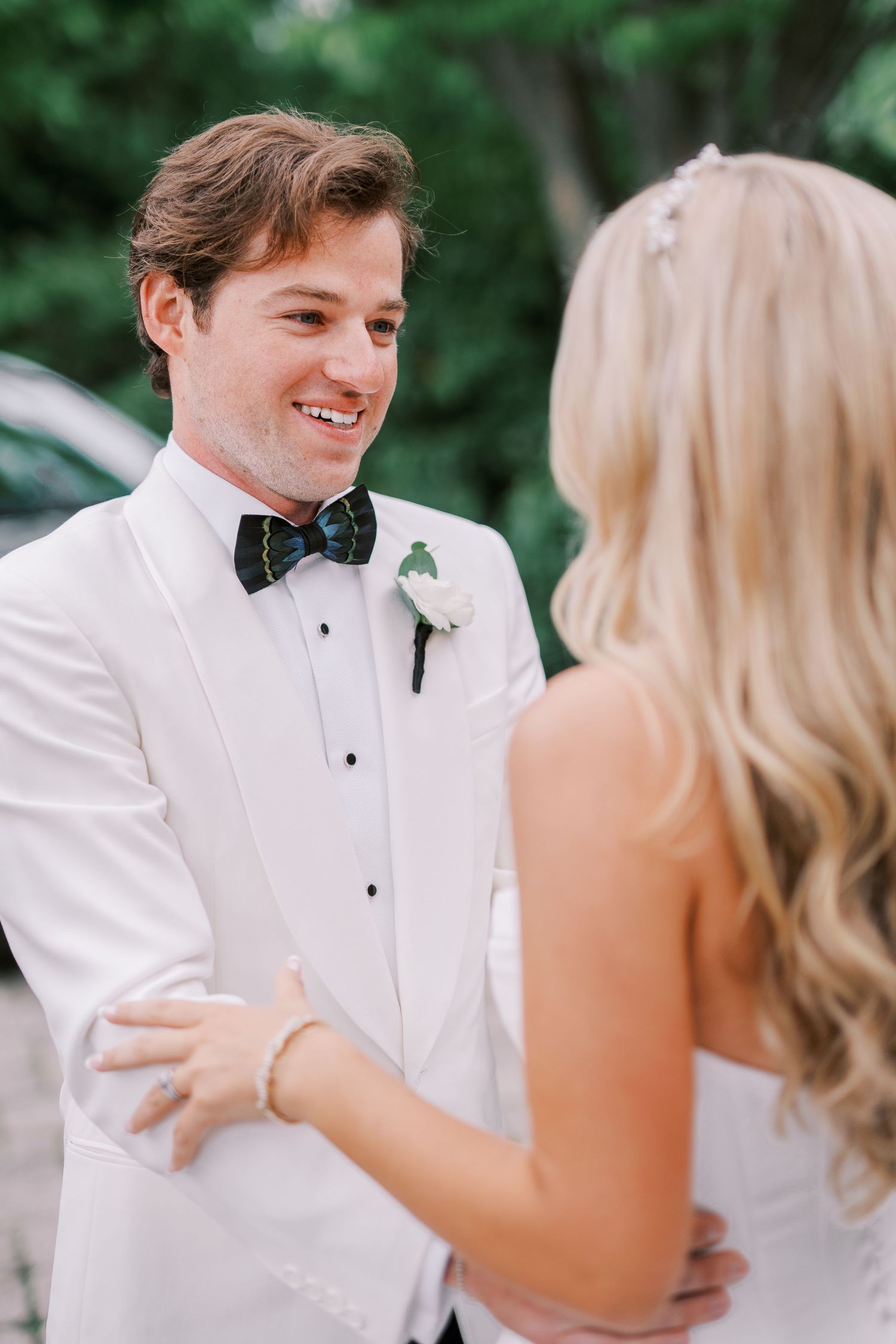 A joyful couple in white wedding attire share an intimate moment outdoors during their wedding celebration.