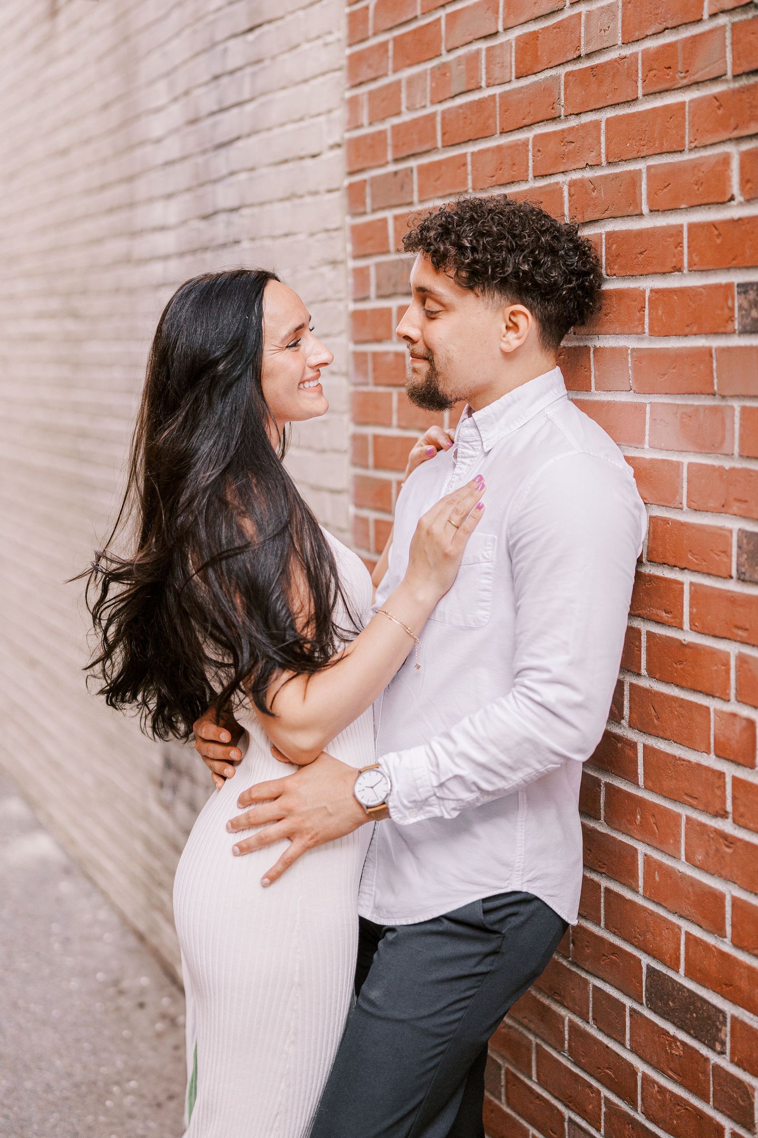 A couple poses lovingly against a brick wall in a romantic photoshoot.