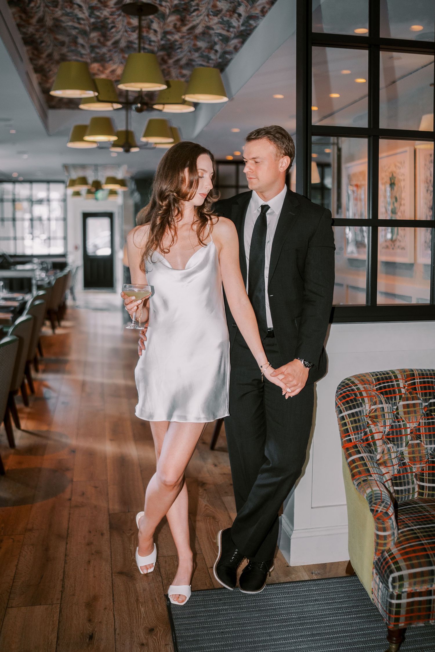 A couple in formal attire shares an intimate dance moment together in an elegantly furnished room.