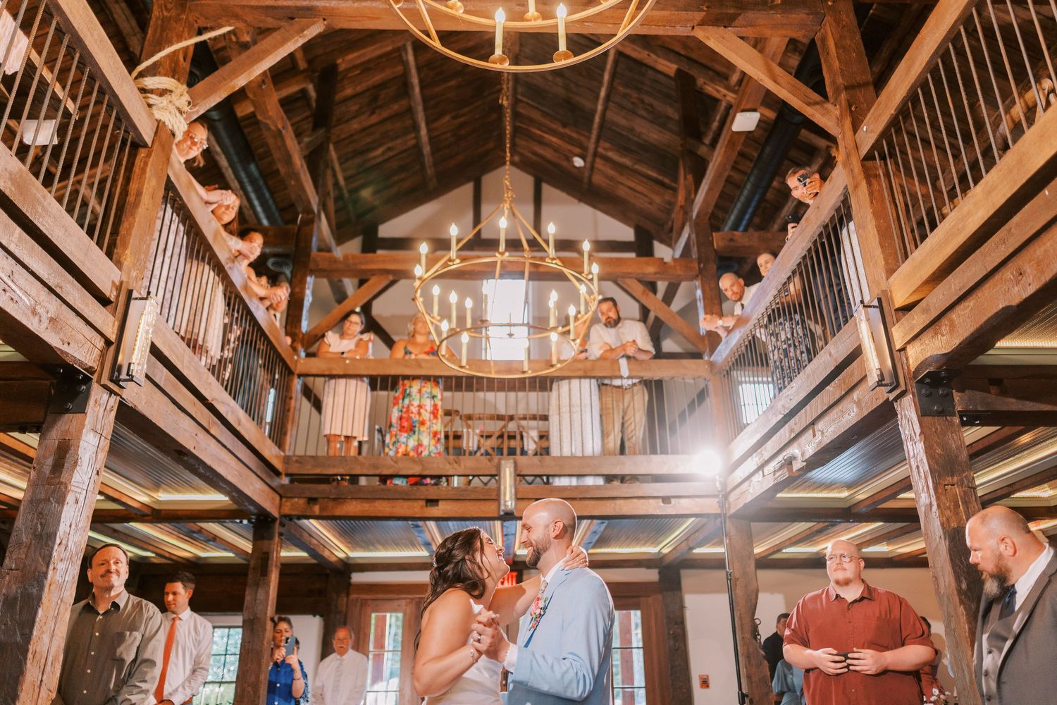 Rustic wooden barn venue interior with exposed beams and chandelier lighting.