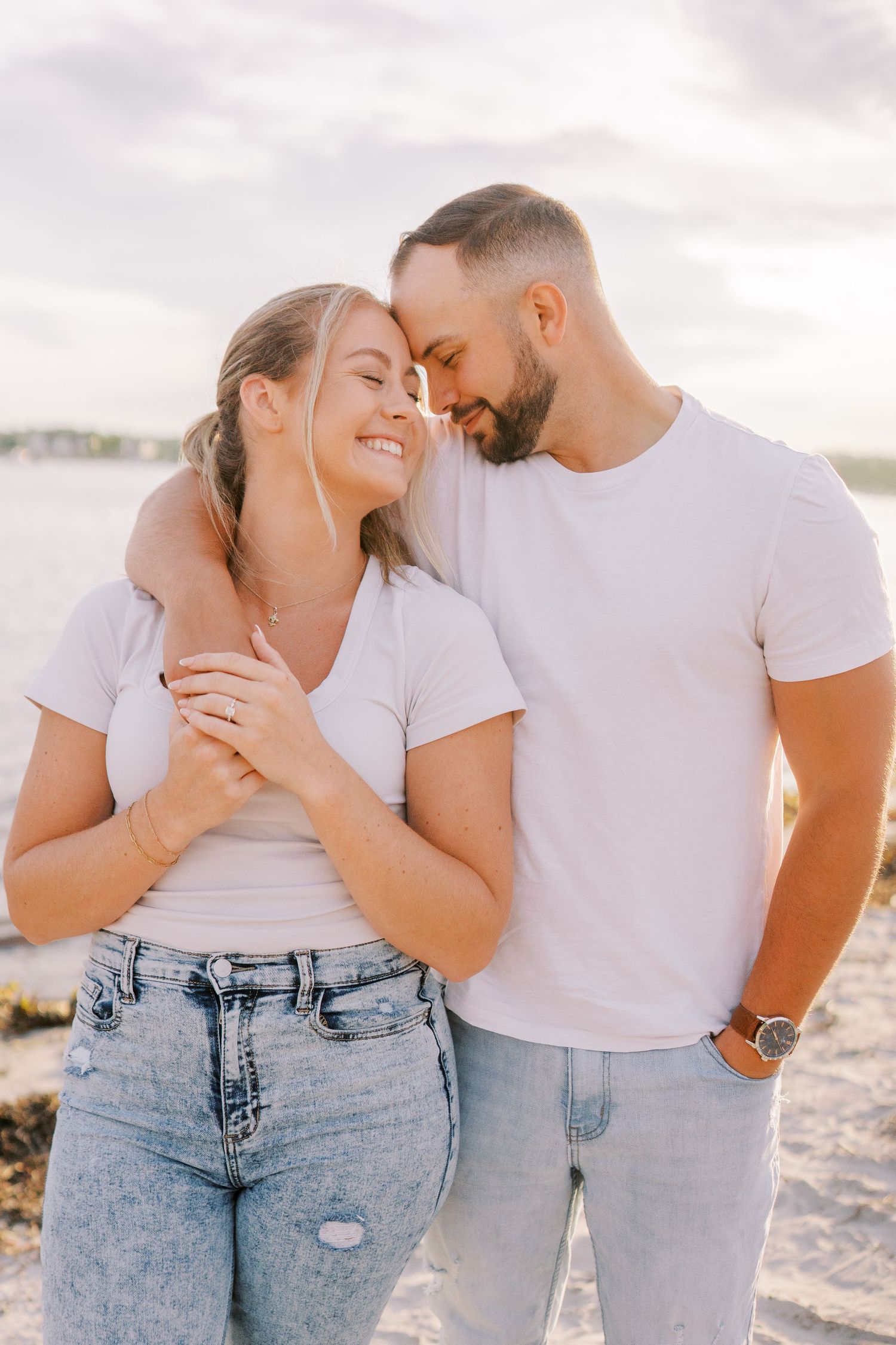 Couple sharing intimate moment on beach with soft sunset lighting.