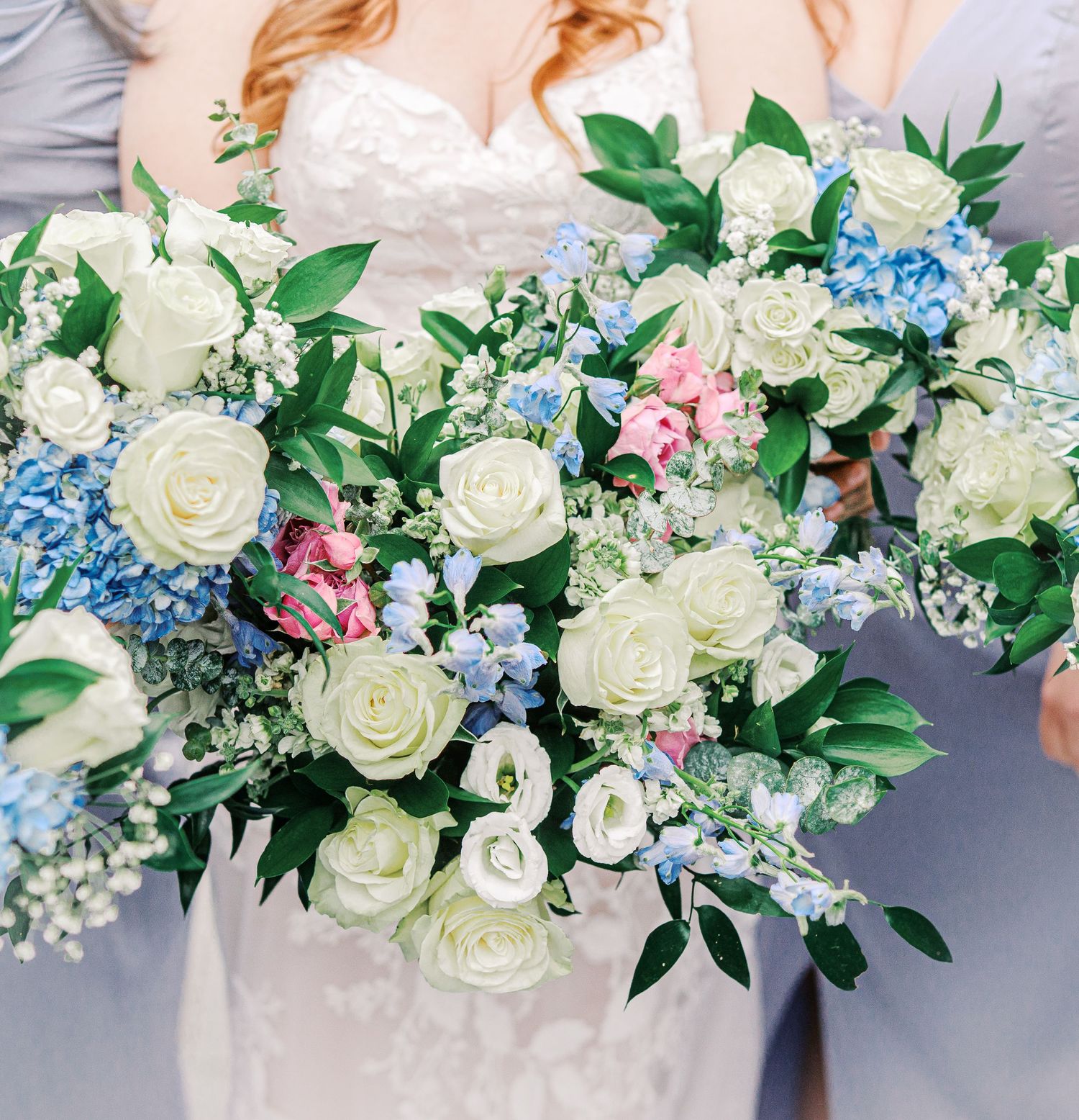 Beautiful wedding bouquet with white roses, blue hydrangeas, pink flowers and greenery against a gray background.