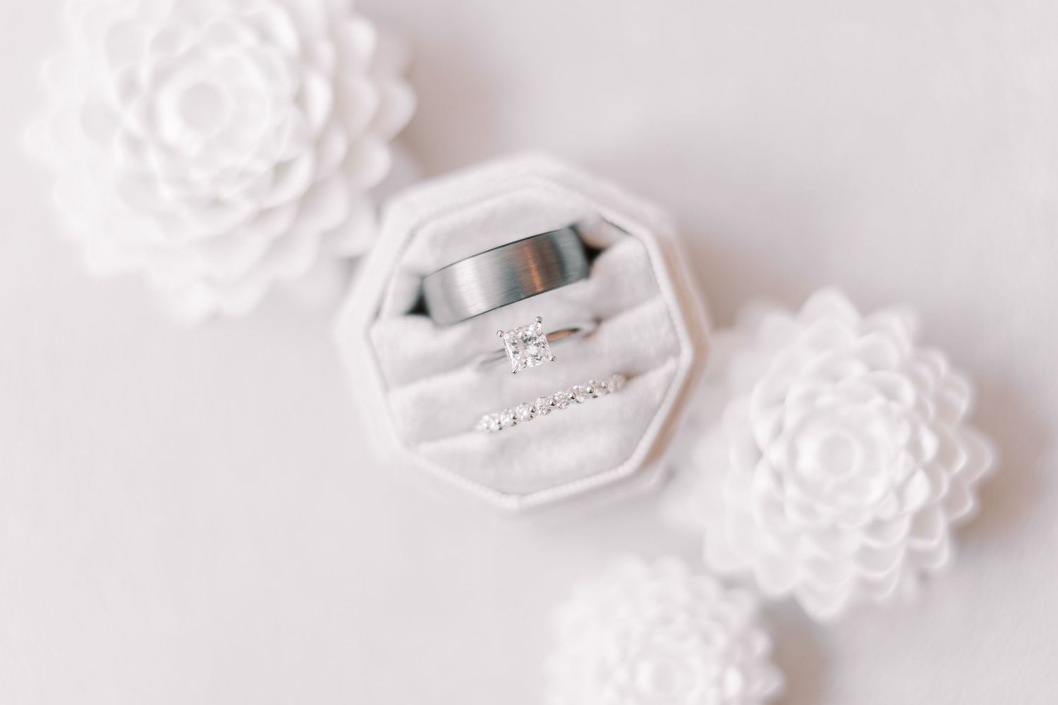 White porcelain ornaments with intricate floral patterns sit scattered on a light surface.