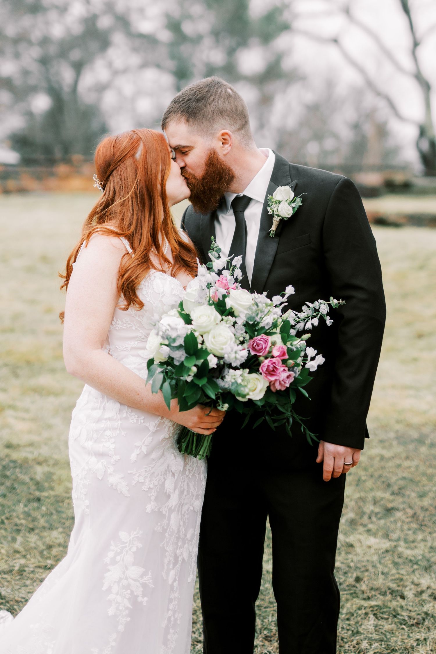 Intimate wedding portrait with elegant floral bouquet against natural backdrop.