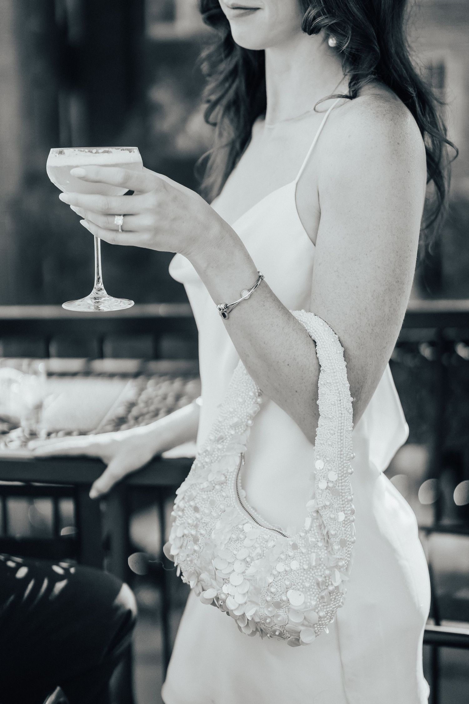 Elegant monochrome image showing a person in a lacy white dress holding a champagne coupe glass.